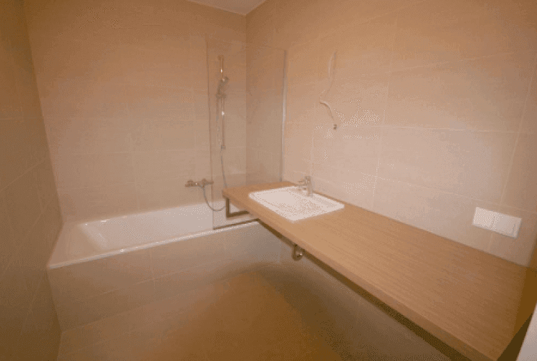 Modernes Badezimmer mit beigefarbenen Fliesen, Badewanne und einem eleganten Einzelwaschbecken.