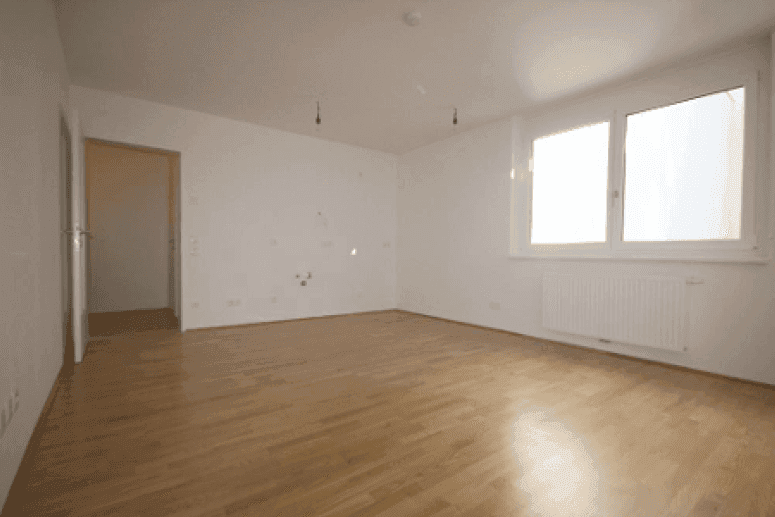 Lichtdurchflutetes Zimmer mit großen Fenstern und hellem Holzparkett, ideal für Wohnzwecke.