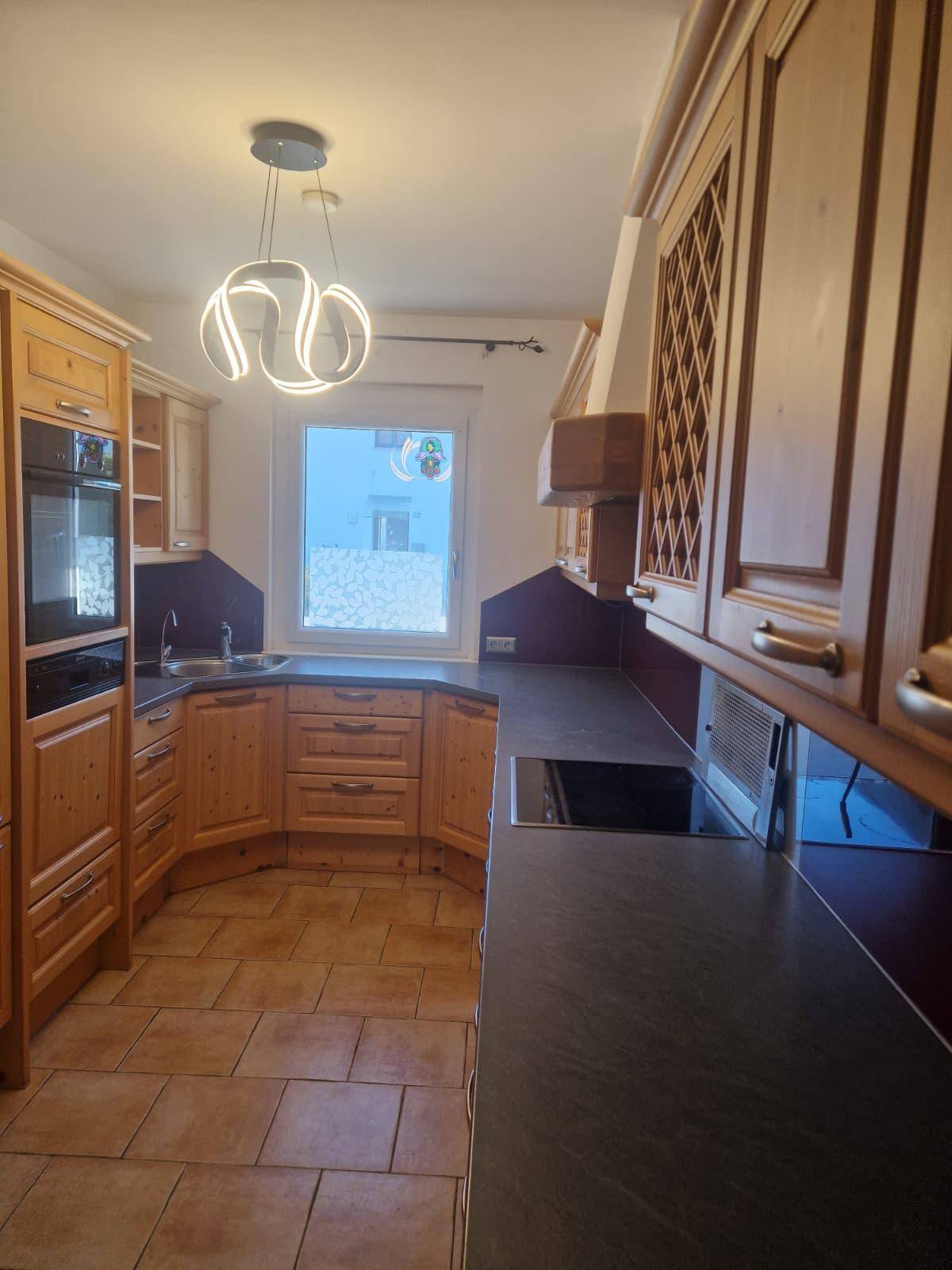 Gemütliche Holzküche mit integriertem Backofen, Spülbecken und Fensterblick.