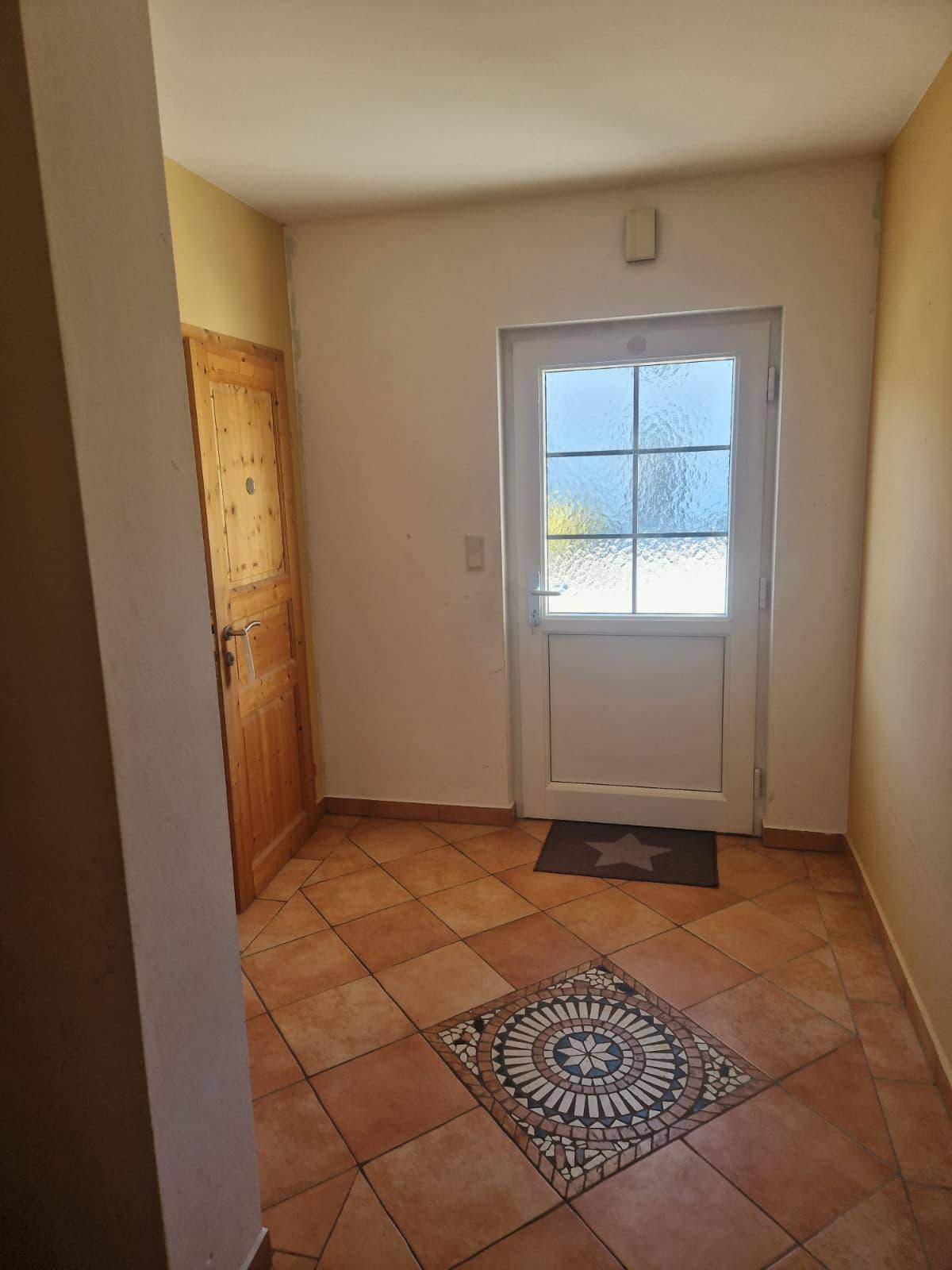 Eingangsbereich mit Terrakotta-Fliesenboden und dekorativem Mosaikmuster.