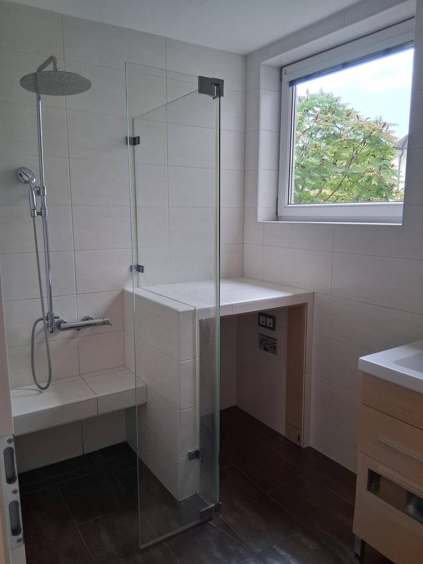 Modernes Badezimmer mit ebenerdiger Dusche, Regendusche und Fenster für natürliches Tageslicht.