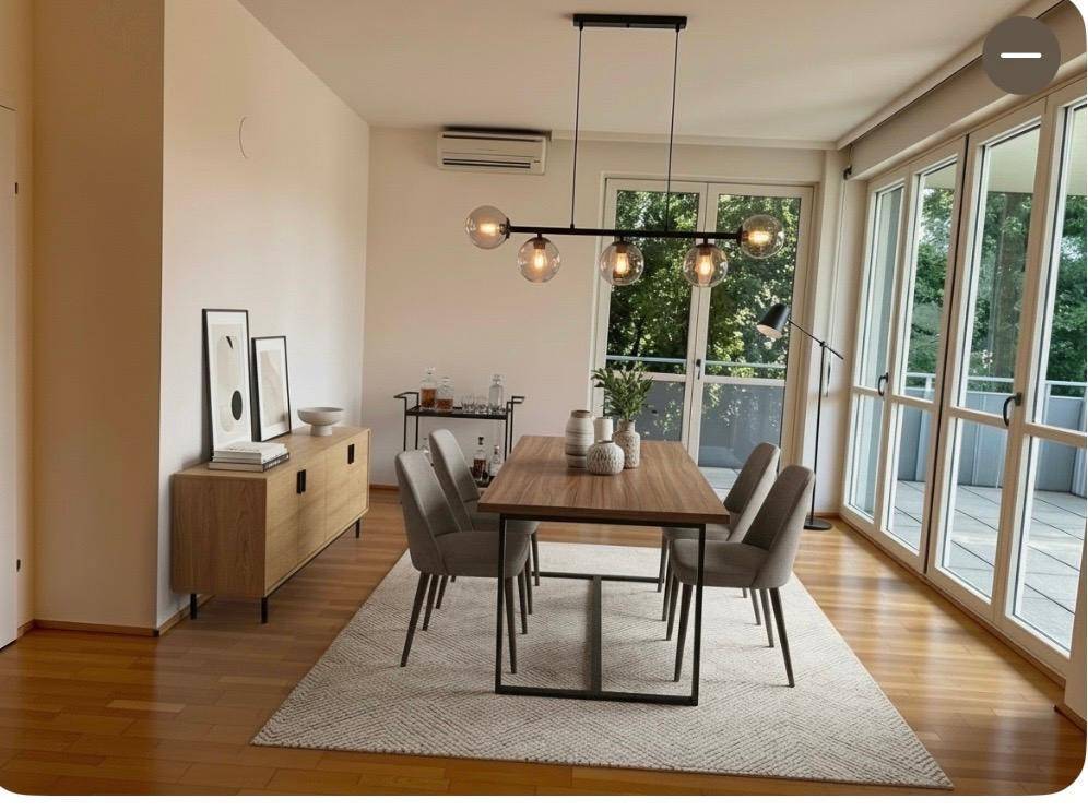 Moderner Essbereich mit Holztisch, bequemen Stühlen und großen Fenstern mit Zugang zum Balkon.