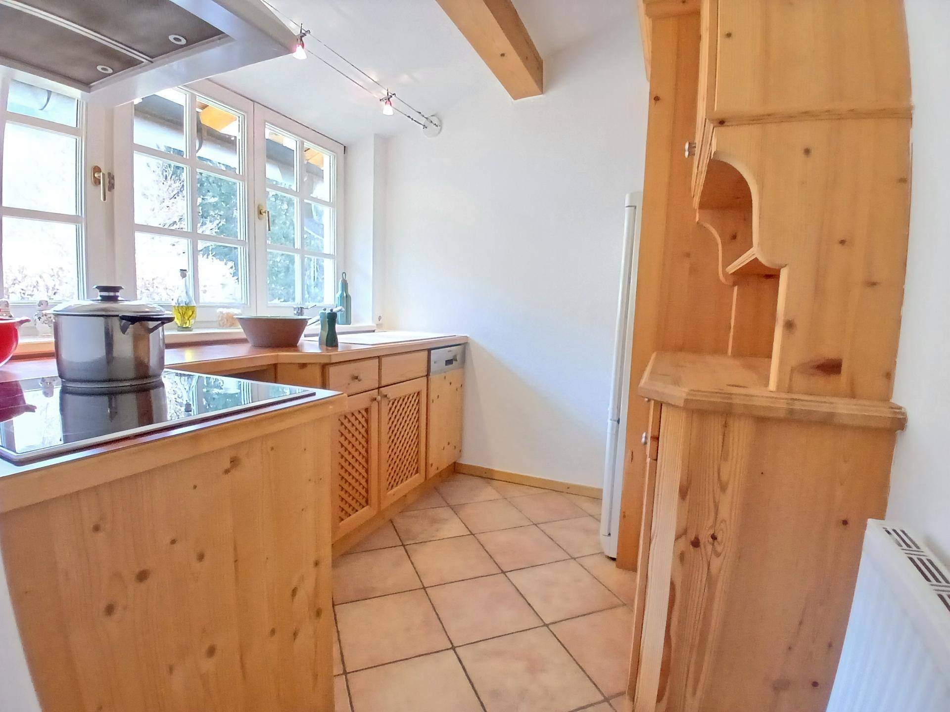 Traditionelle Holzküche mit Fliesenboden, Spülmaschine und großem Fenster.