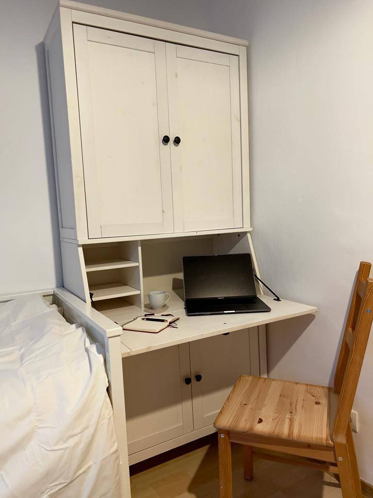 Funktionaler Arbeitsbereich mit Klappschreibtisch und Stauraum neben dem Schlafbereich in einem Studio.