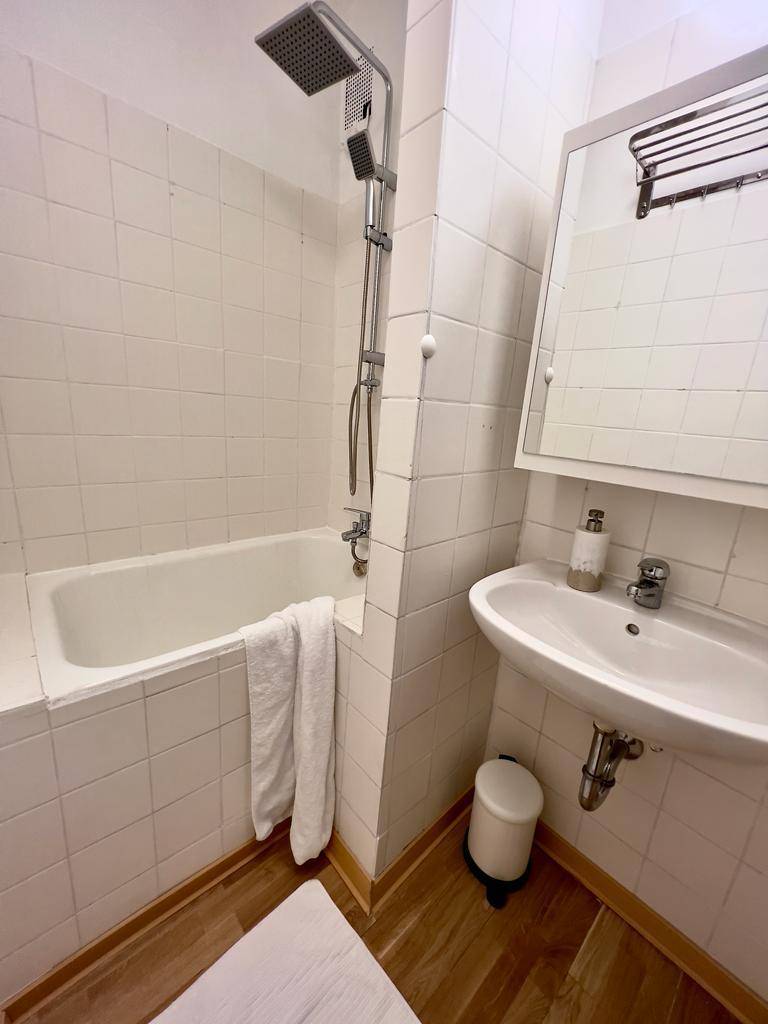 Helles Badezimmer mit Badewanne, integrierter Dusche, Waschbecken und Spiegelschrank.