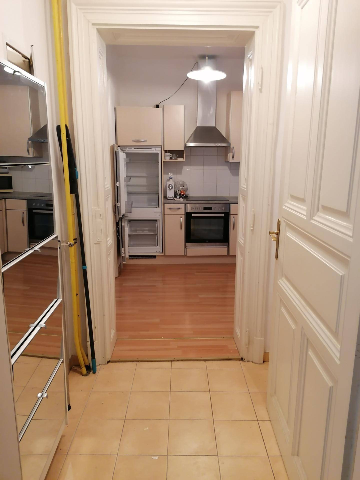 Blick vom Flur in die Küche mit offenem Kühlschrank und funktionaler Ausstattung.