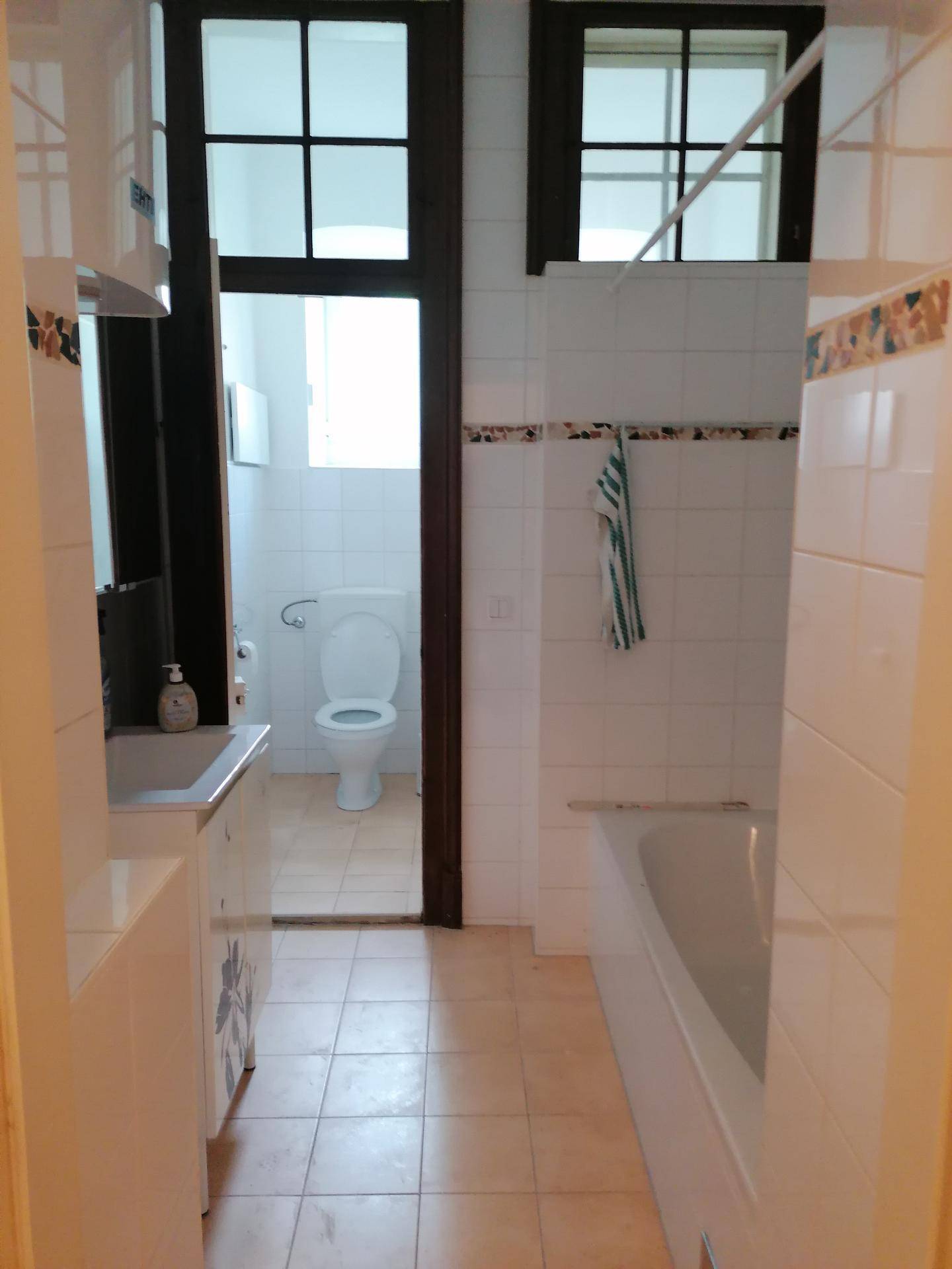 Helles Badezimmer mit Badewanne, Waschbecken und separatem WC-Bereich.