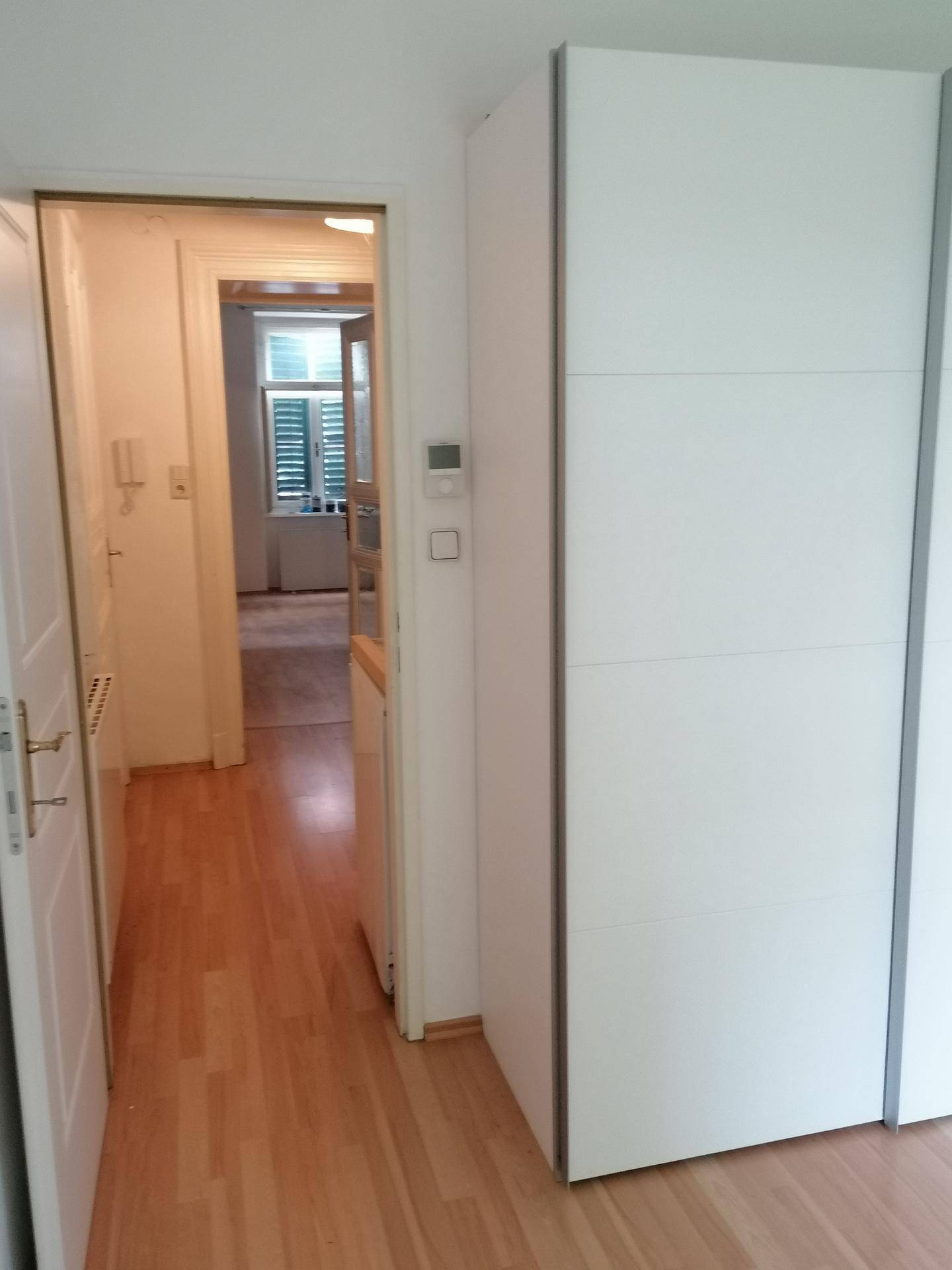 Heller Flur mit Holzboden und praktischem Einbauschrank, der zu weiteren Räumen führt.