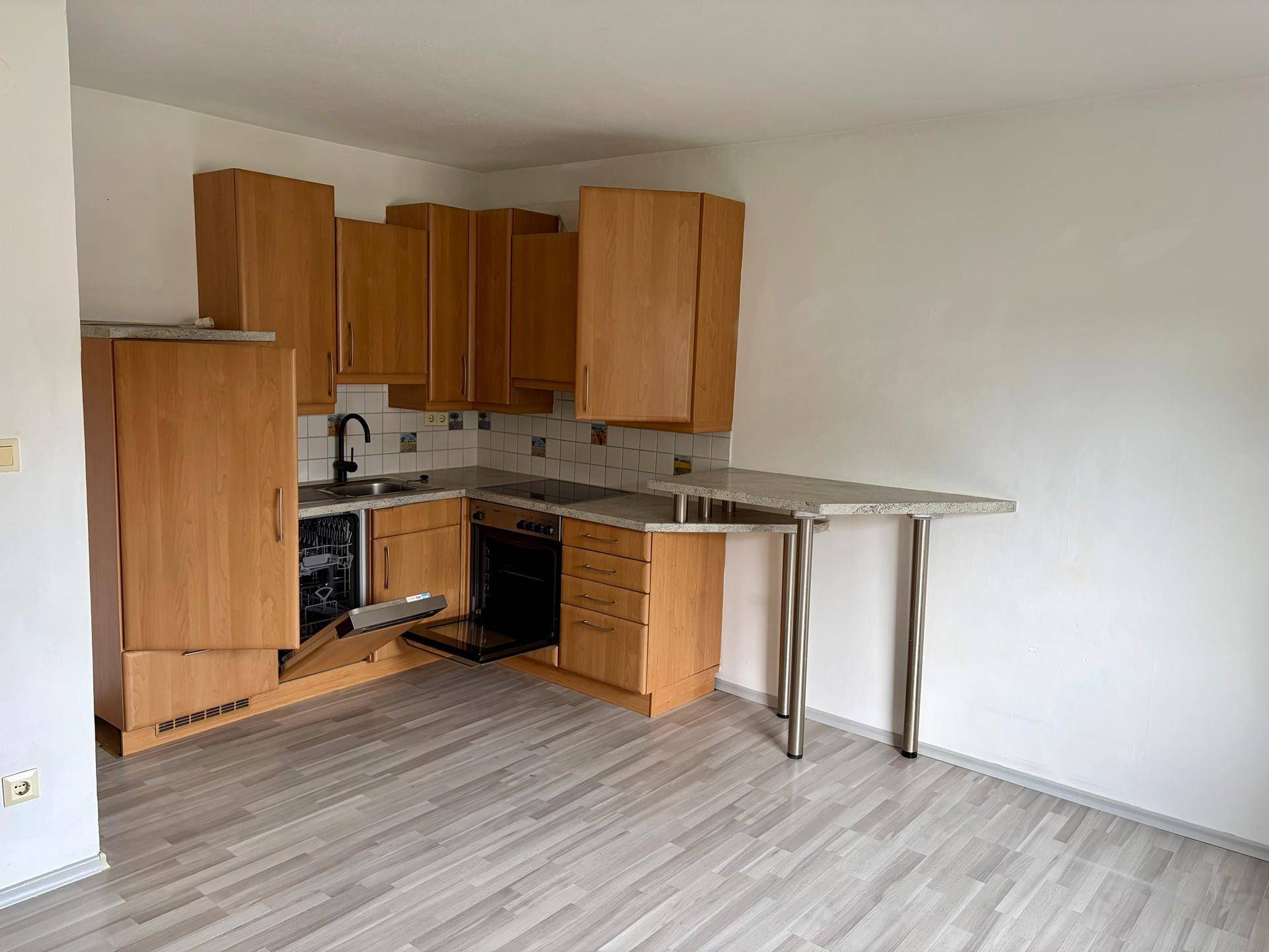 Einbauküche mit Holzschränken, Spülmaschine und integriertem Frühstückstresen.