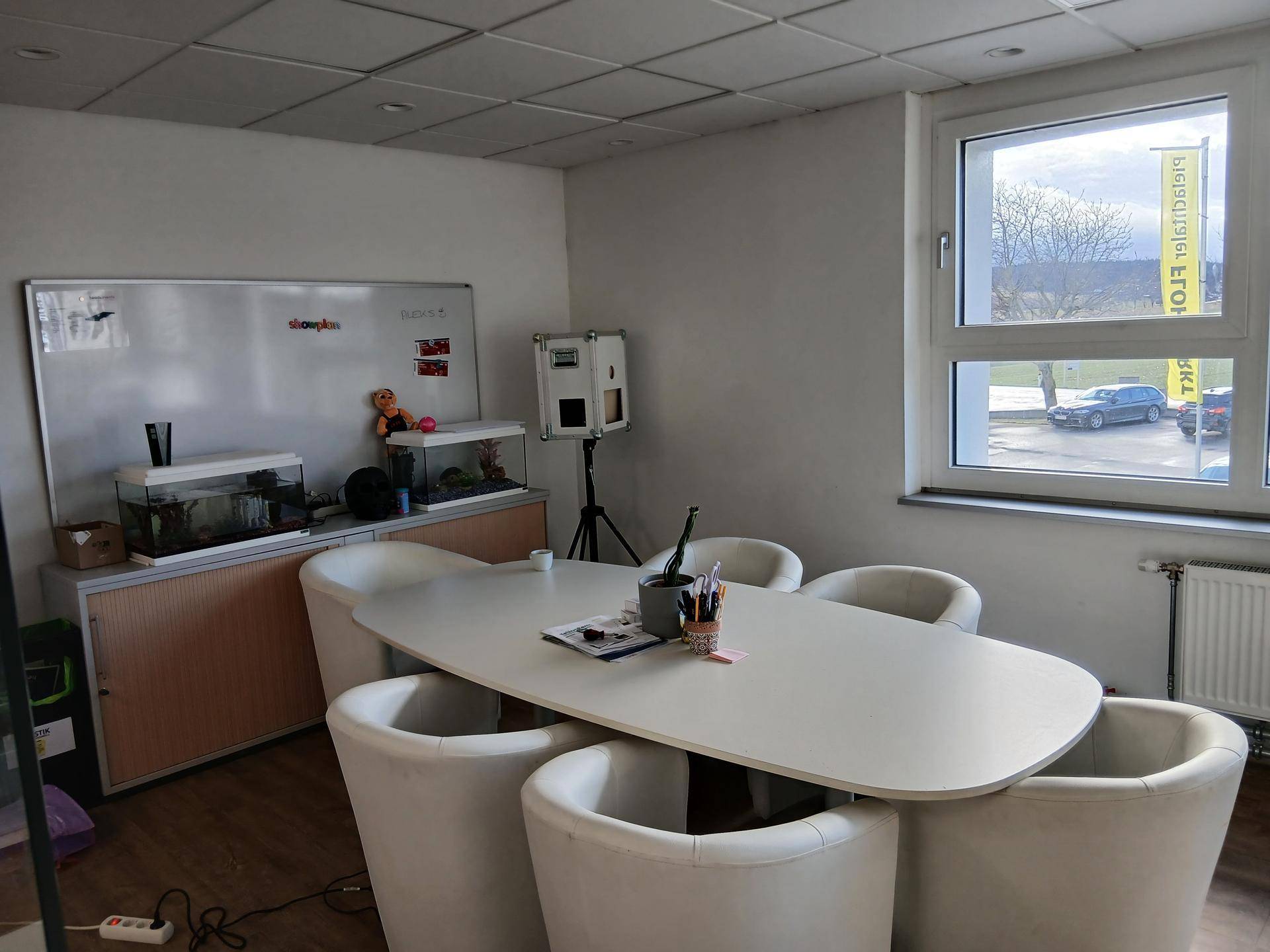 Detailansicht des Besprechungsbereichs mit Tisch, Stühlen und Fensterblick auf die Straße.