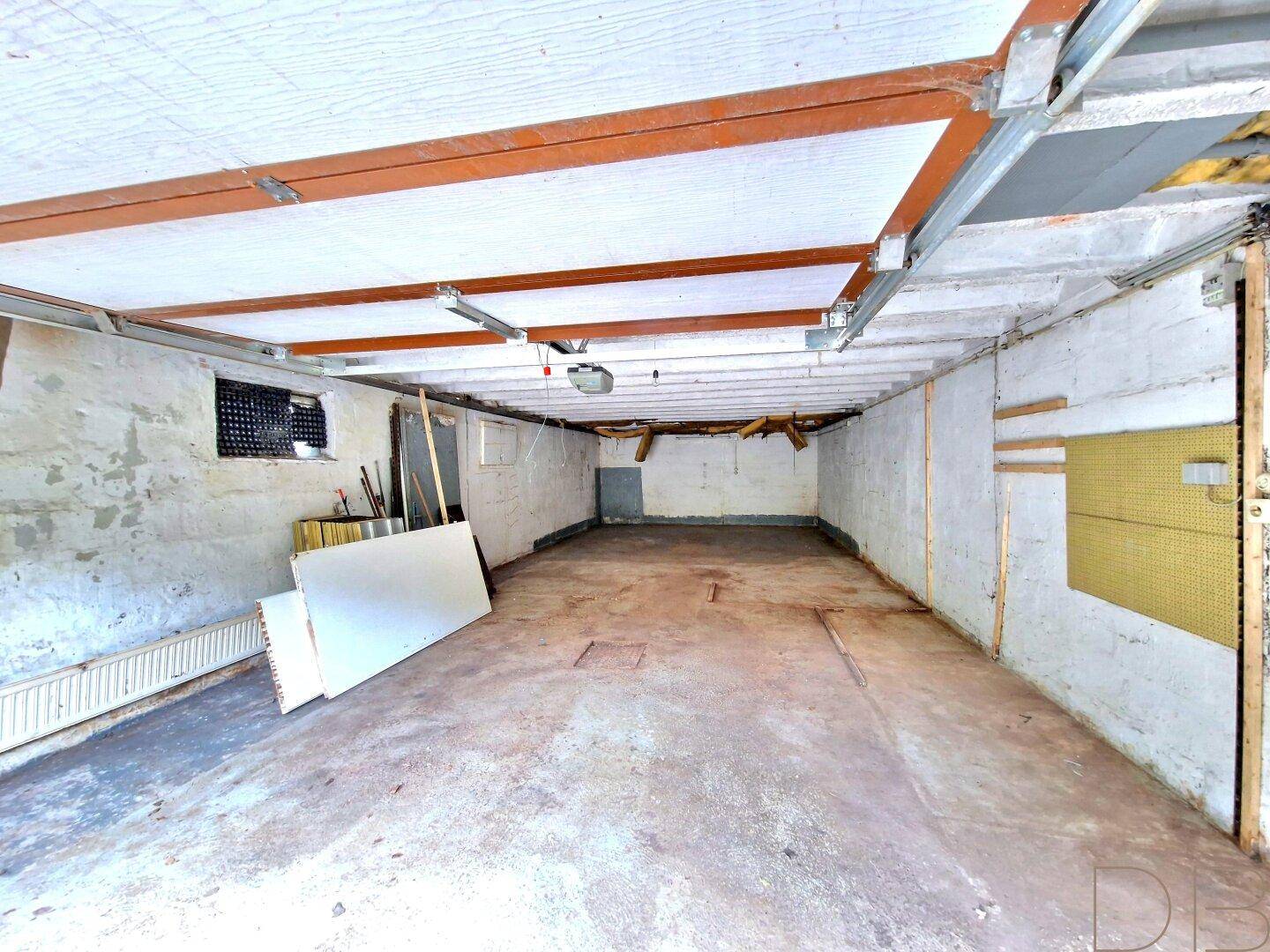 Geräumige Garage oder Lagerfläche mit Betonboden und sichtbaren Deckenbalken.