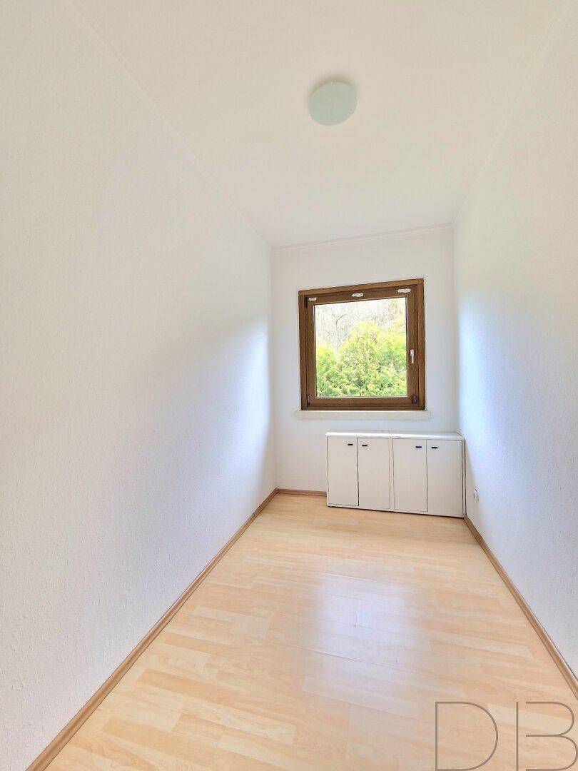 Kleiner, heller Raum mit Laminatboden und Fenster mit Blick ins Grüne.