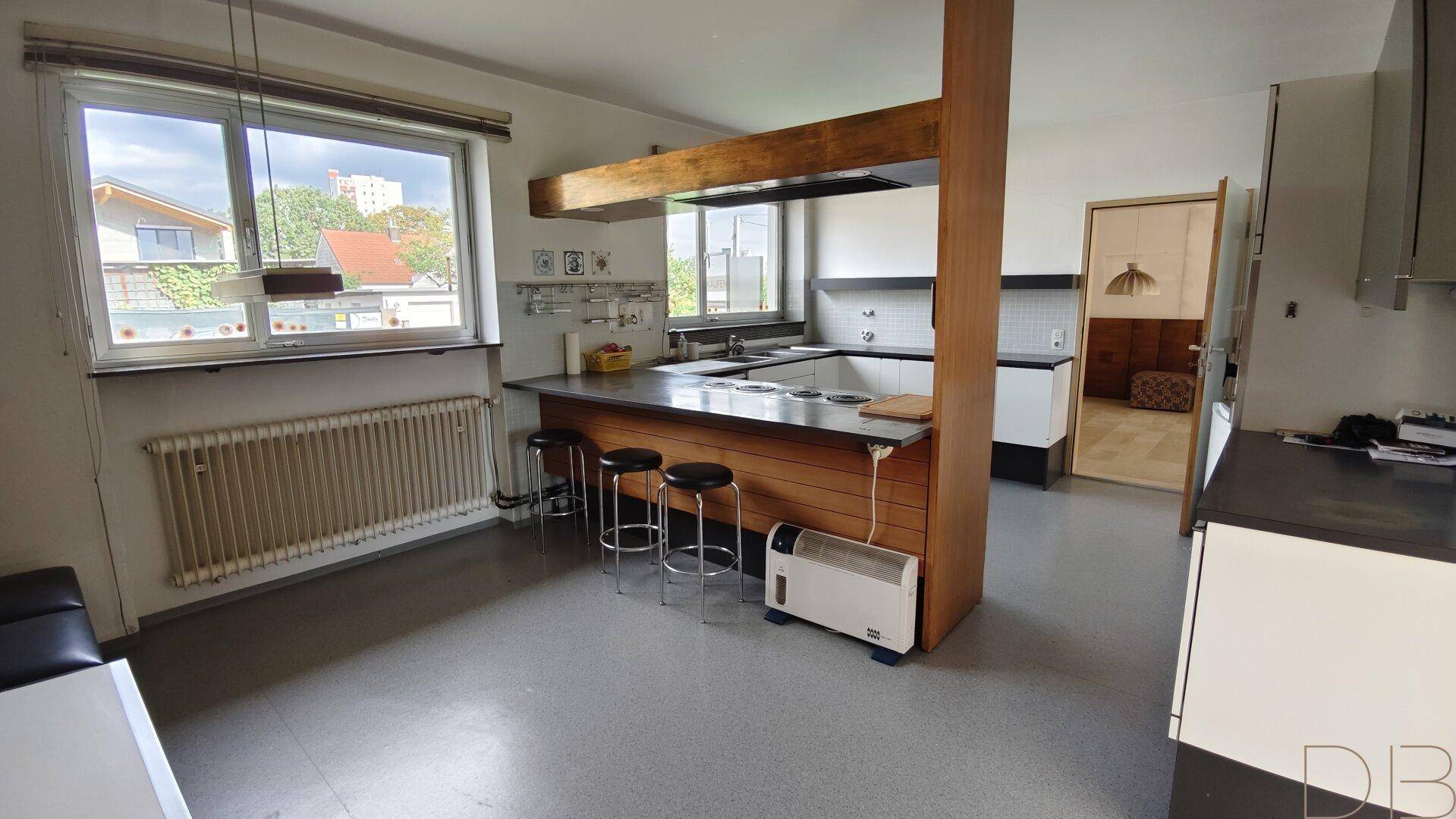 Geräumige Küche mit Kochinsel, Barhockern und Blick nach draußen.