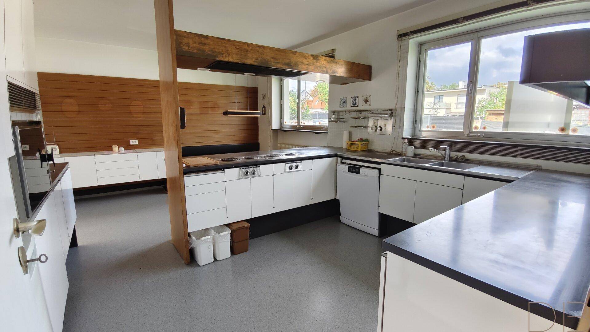 Funktionale Küche mit weißen Schränken, Arbeitsplatten und integrierten Geräten.