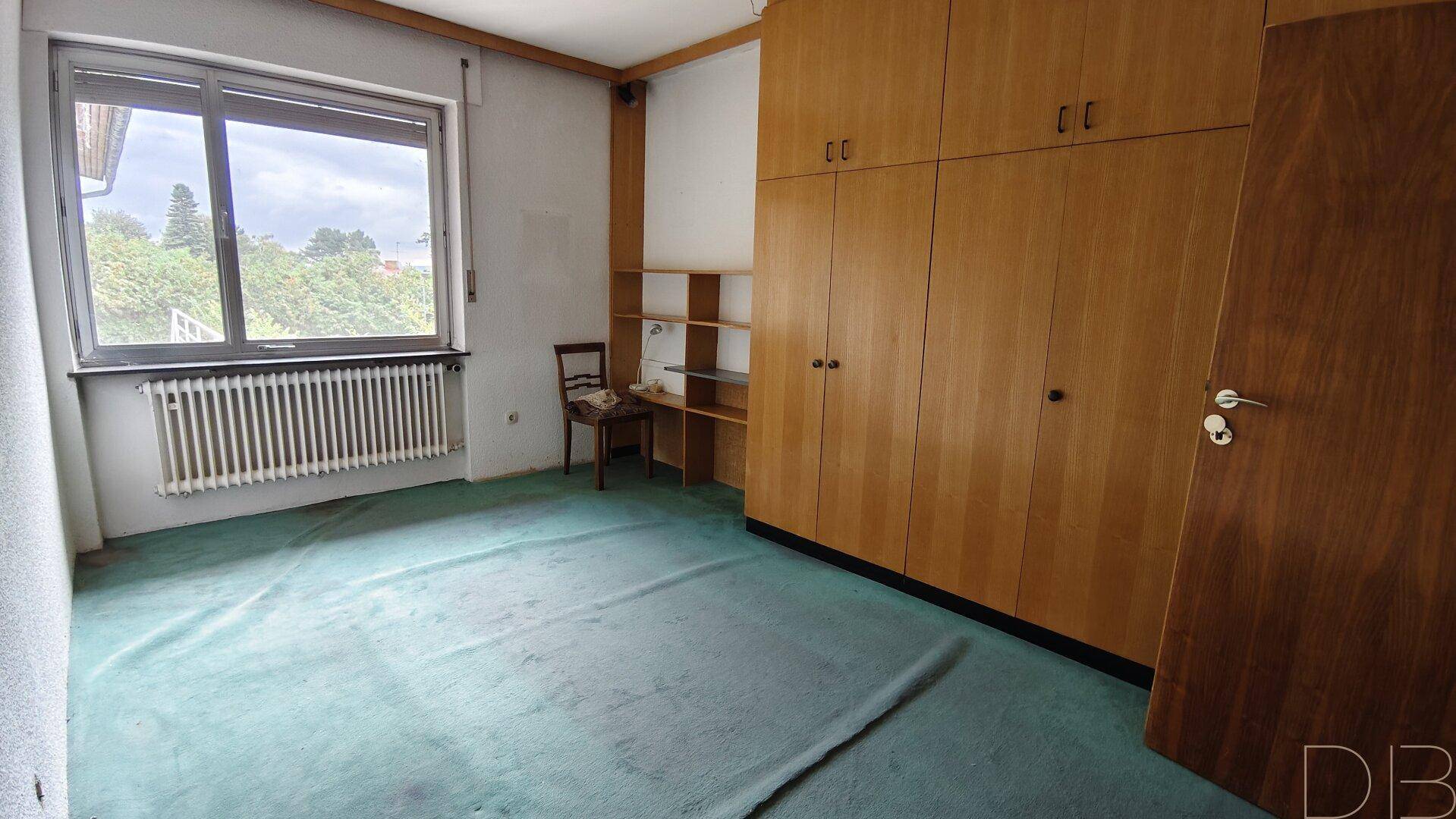 Schlafzimmer mit Teppichboden, Einbauschränken und großem Fenster.