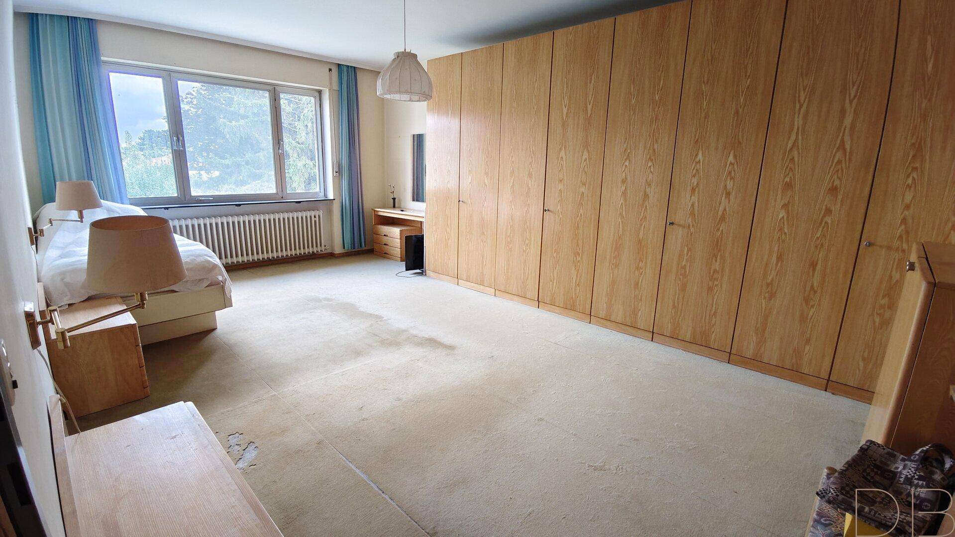 Geräumiges Schlafzimmer mit Teppichboden, Einbauschränken und großem Fenster.