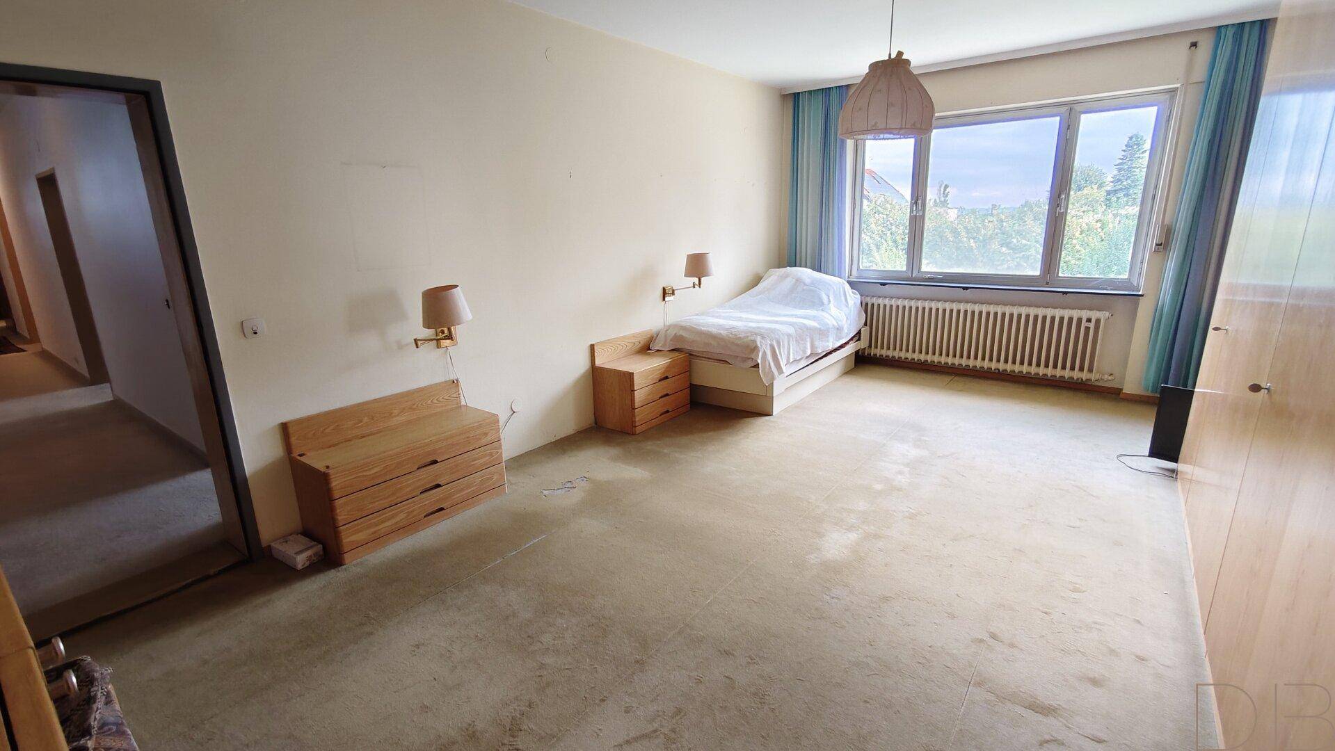 Schlafzimmer mit Teppichboden, Einzelbett und Einbauschränken.