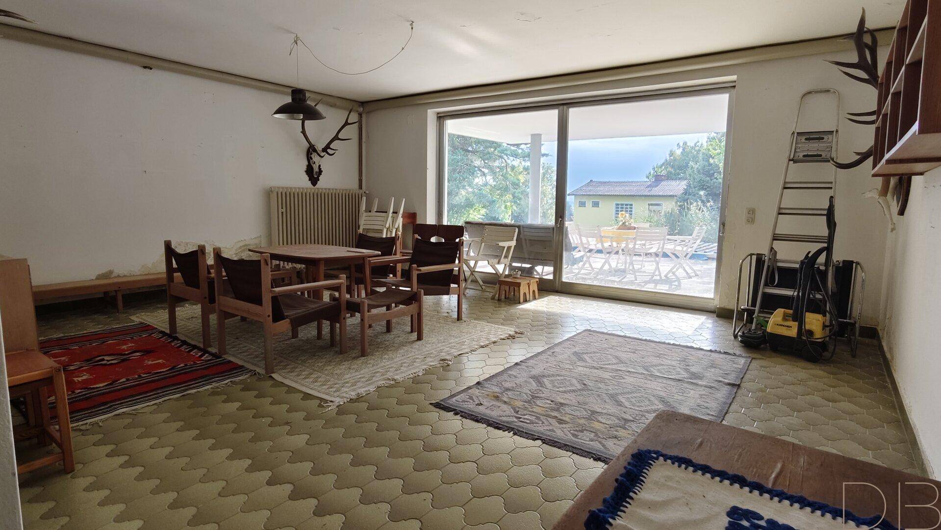 Geräumiger Hobbyraum mit Fliesenboden, Esstisch und Zugang zur Terrasse.