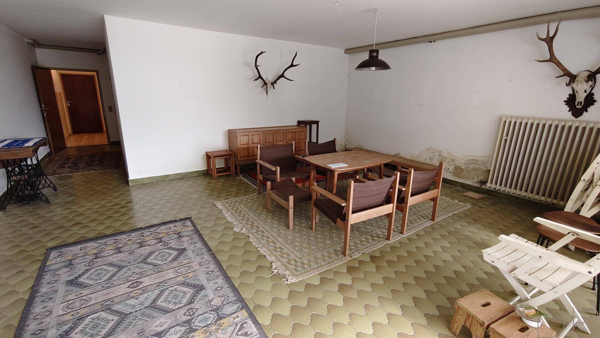 Großer Hobbyraum mit Fliesenboden, Esstisch und Hirschgeweih-Dekoration.