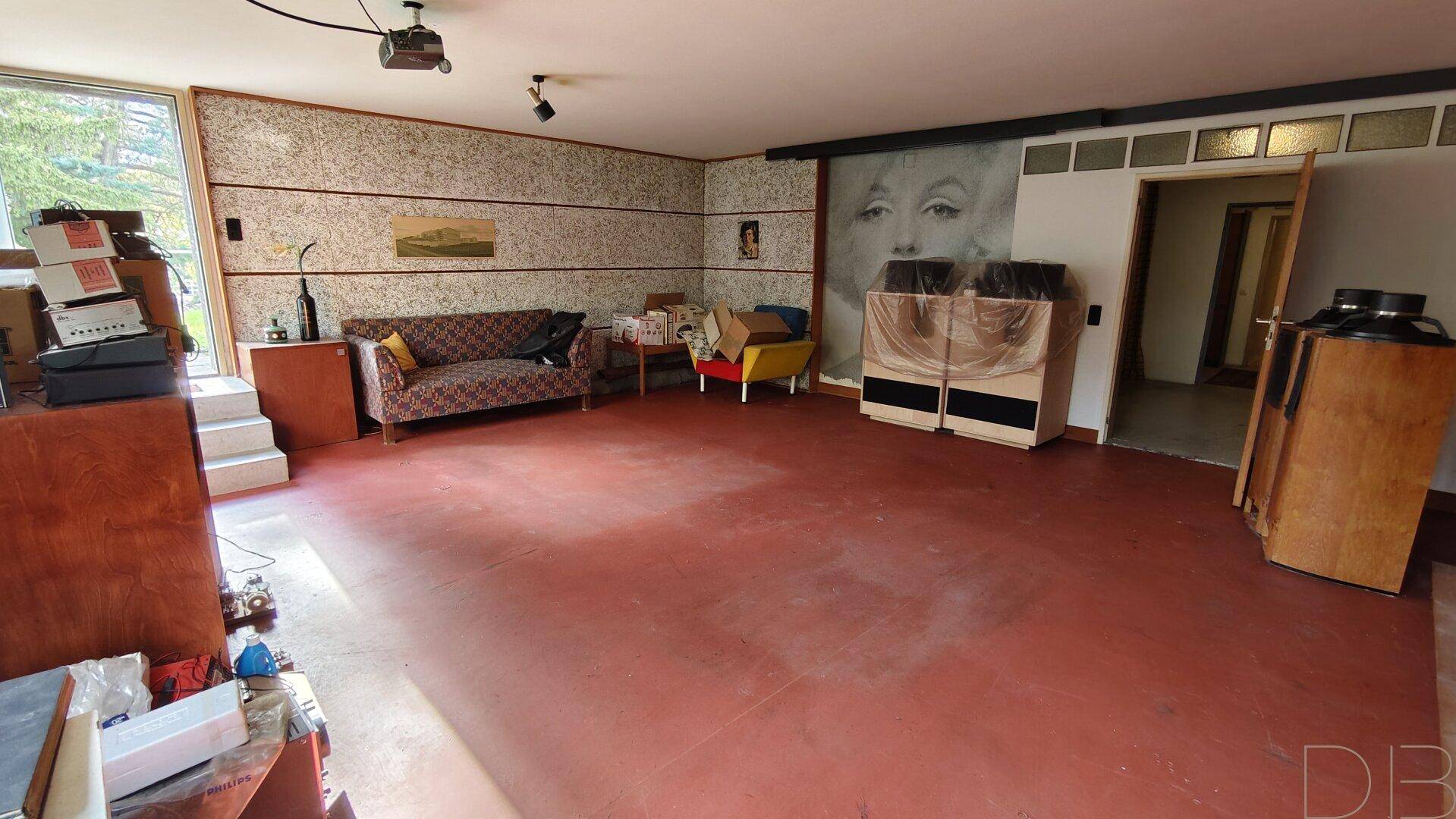 Großer Kellerraum mit rotem Boden, Marilyn Monroe Wandbild und Stauraum.