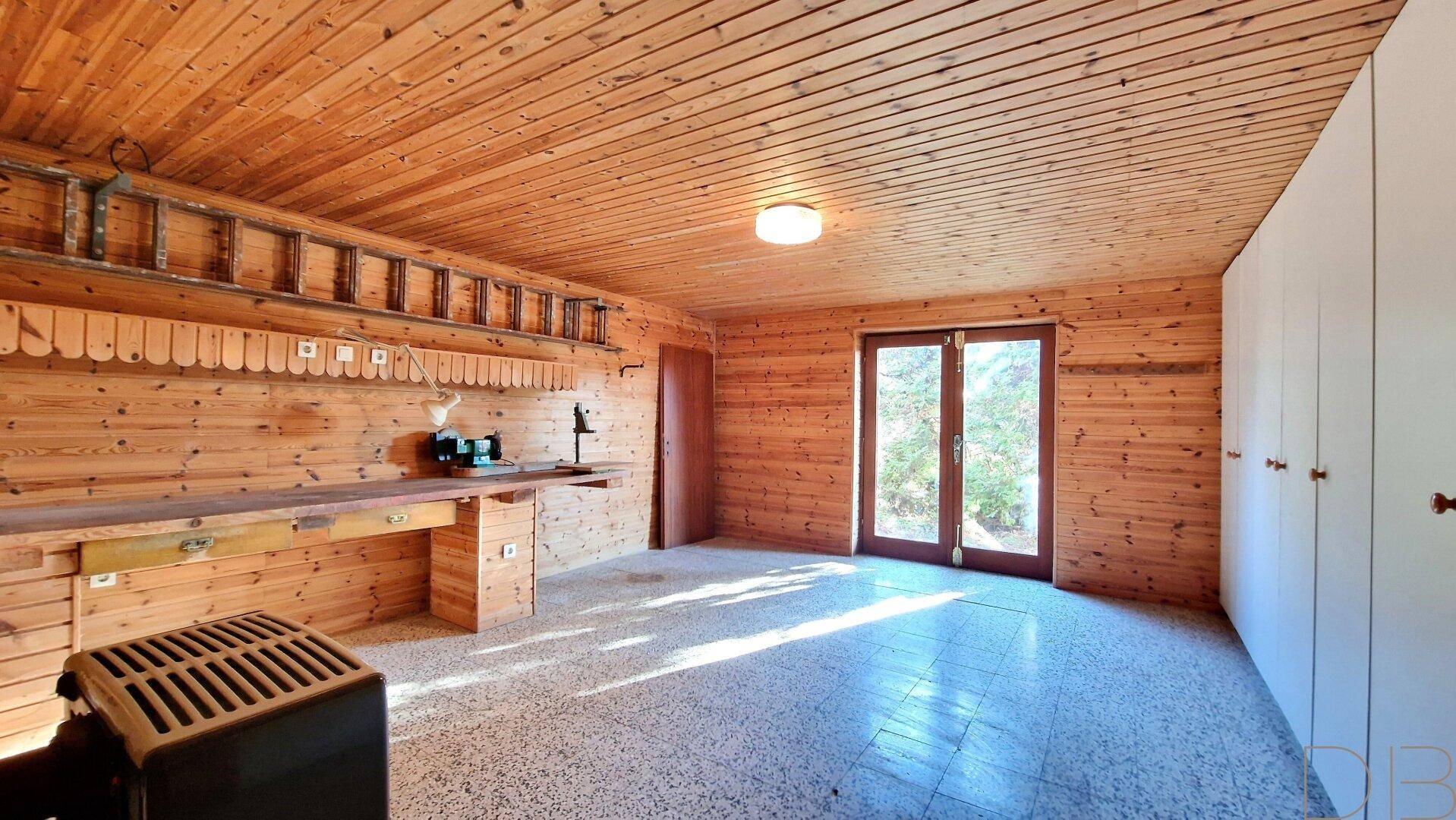 Geräumiger Hobbyraum mit Holzvertäfelung, Werkbank und Zugang zum Außenbereich.