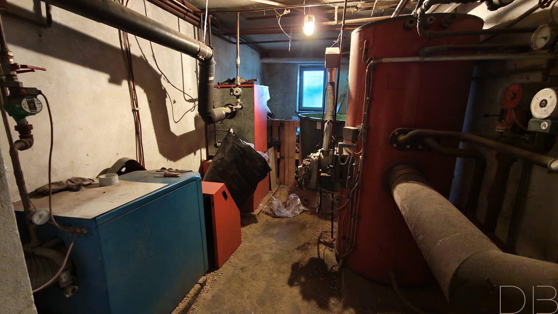 Heizungsraum im Keller mit großen Warmwasserspeichern und Rohren, zeigt die technische Ausstattung.