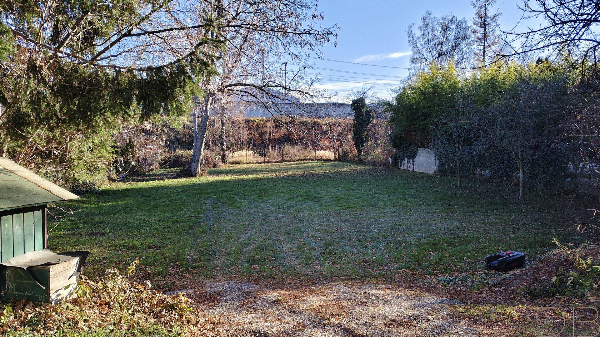 Weitläufige Gartenfläche mit einem kleinen Schuppen und umgebender Vegetation.