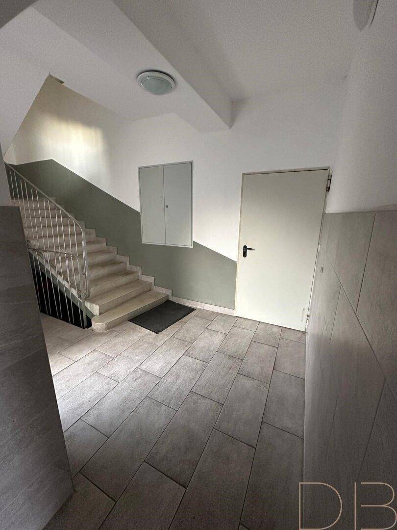 Helles Treppenhaus mit Fliesenboden und schlichtem Design, verbindet die Stockwerke.
