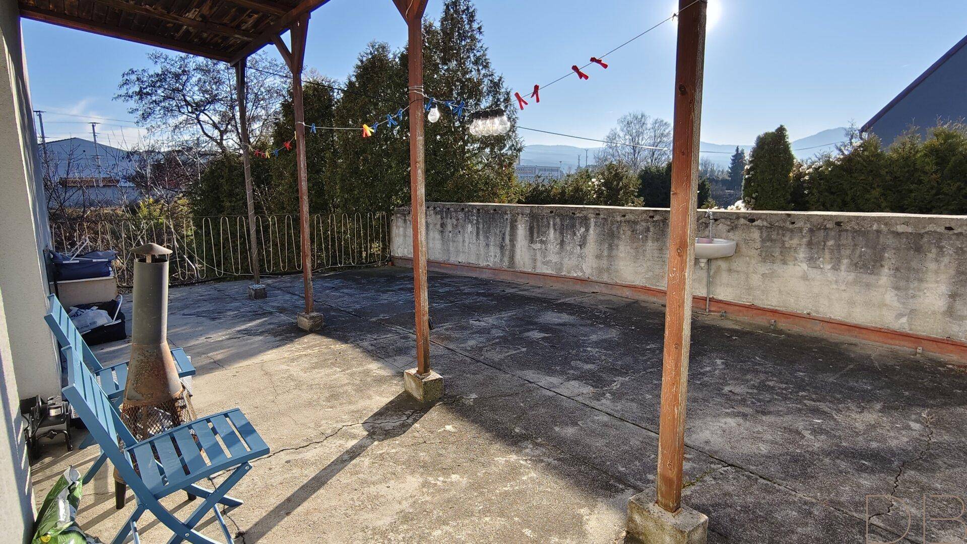 Große, überdachte Terrasse mit Holzbalken und Blick ins Grüne, ideal für Outdoor-Aktivitäten.