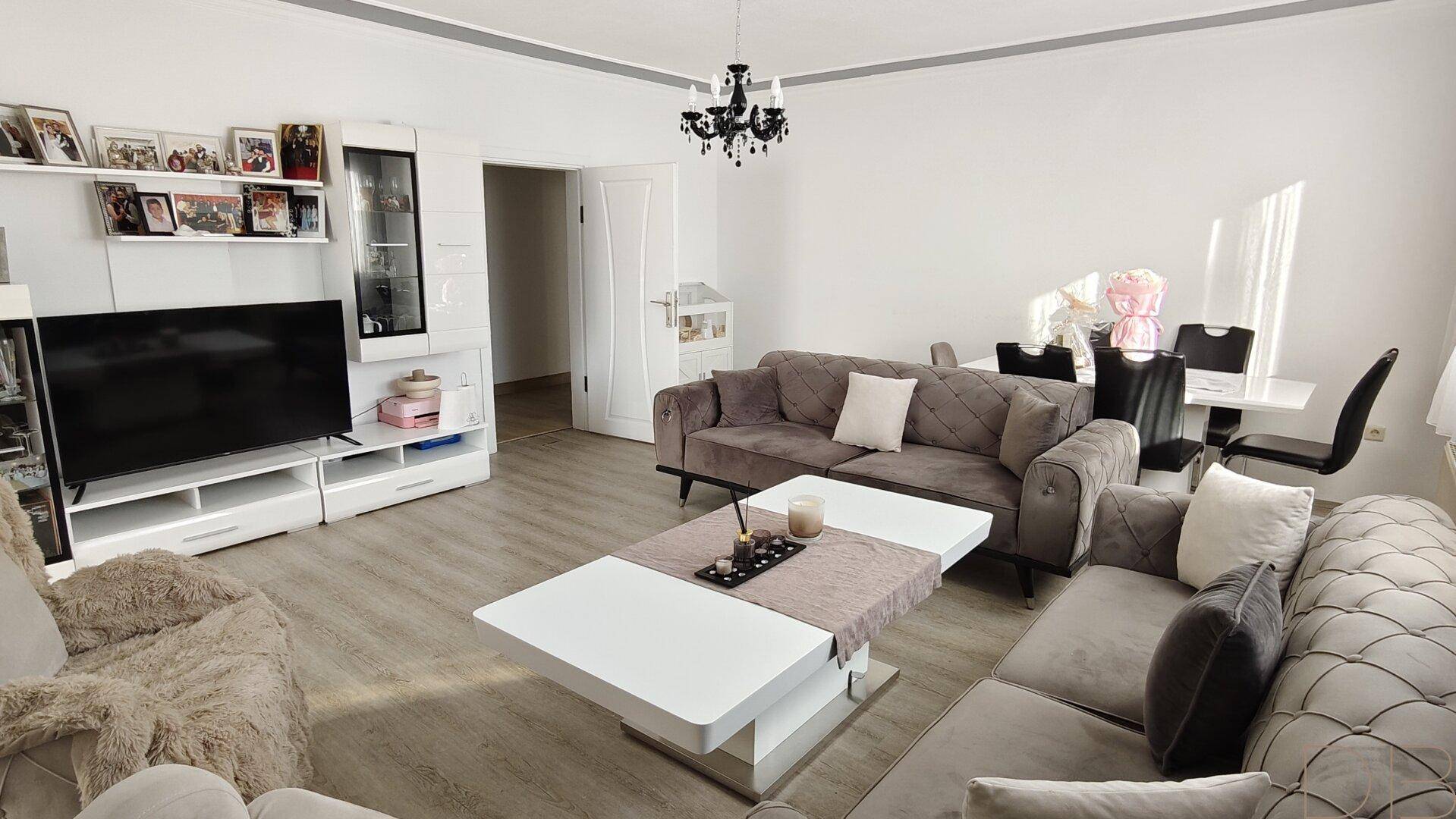 Heller Wohn- und Essbereich mit modernem Dekor, bequemen Sofas und Laminatboden.