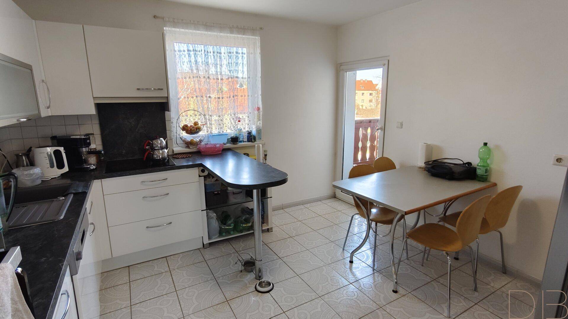 Küche mit Essbereich, Fenster und Zugang zum Balkon, bietet viel Tageslicht.