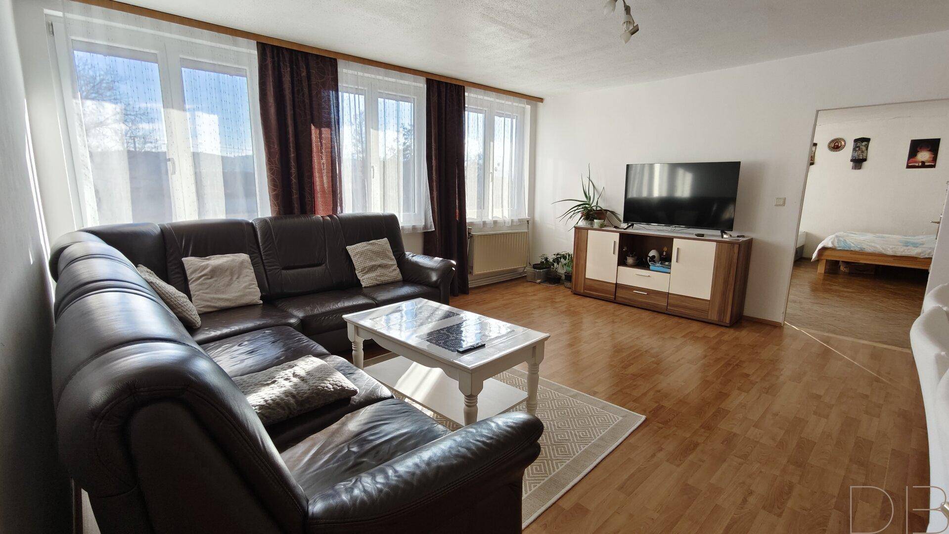 Gemütliches Wohnzimmer mit großem Ledersofa und Holzboden, bietet viel Platz zum Entspannen.