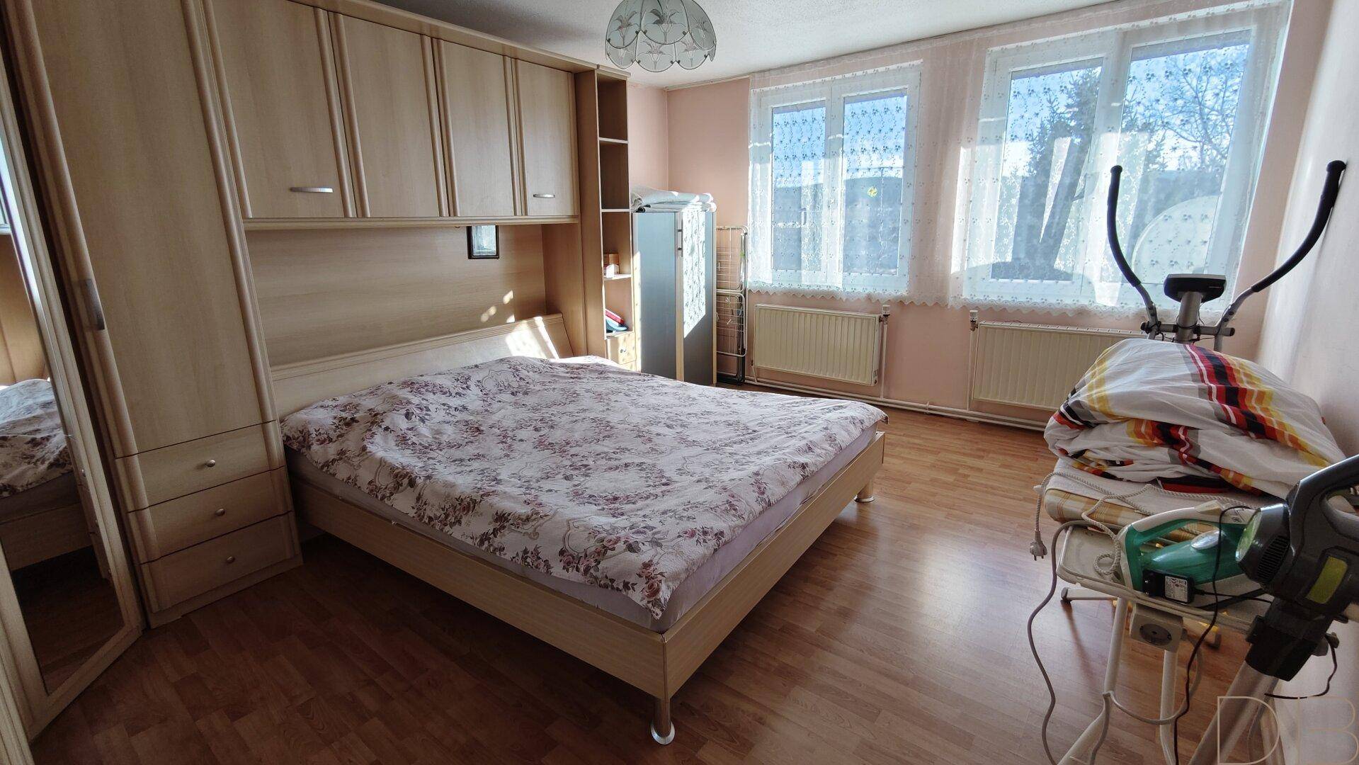 Geräumiges Schlafzimmer mit Einbauschränken, Doppelbett und großen Fenstern.