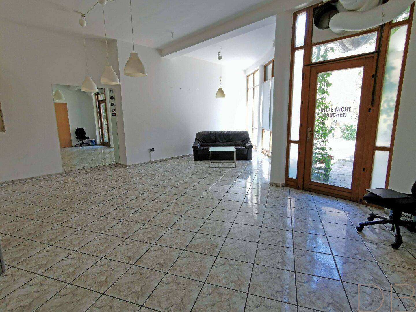 Geräumiger, heller Gewerberaum mit Fliesenboden und direktem Zugang zum Außenbereich.