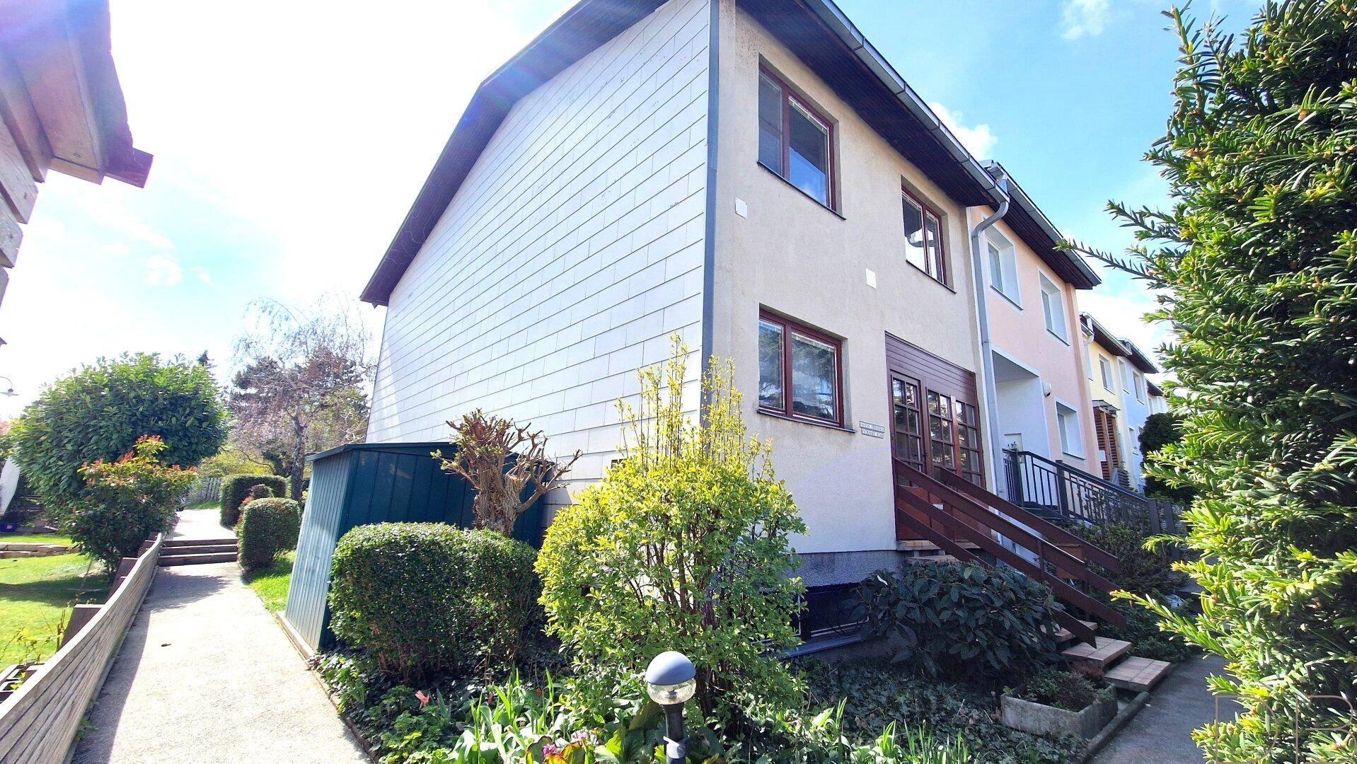 Seitenansicht des Hauses mit einem Weg, einem Gartenschuppen und einer Treppe.