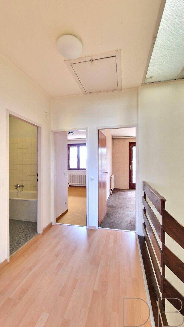 Heller Flur im Obergeschoss mit Holzboden und Zugang zu mehreren Zimmern.