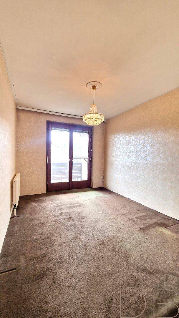 Unmöbliertes Zimmer mit Teppichboden und einer Doppeltür, die ins Freie führt.