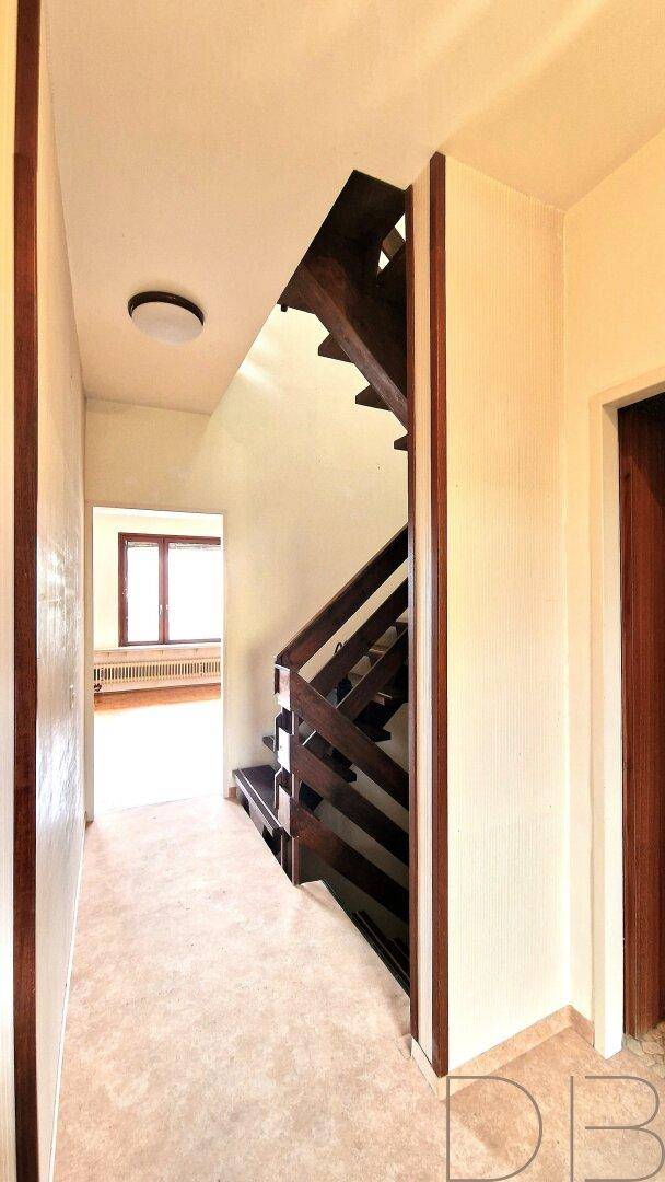 Heller Flur mit Holztreppe, die in das obere Stockwerk führt.