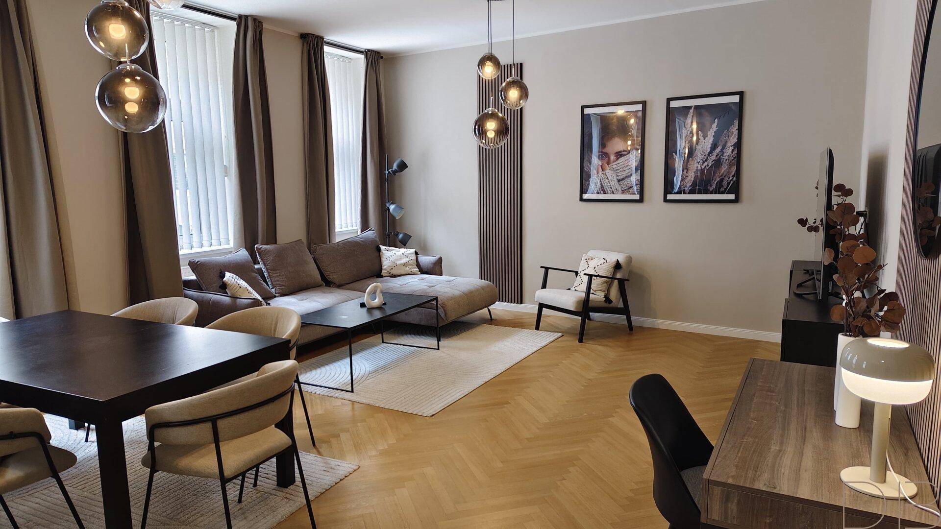 Gemütlicher Wohnbereich mit Ecksofa, Esstisch und modernem Fischgrätparkett.