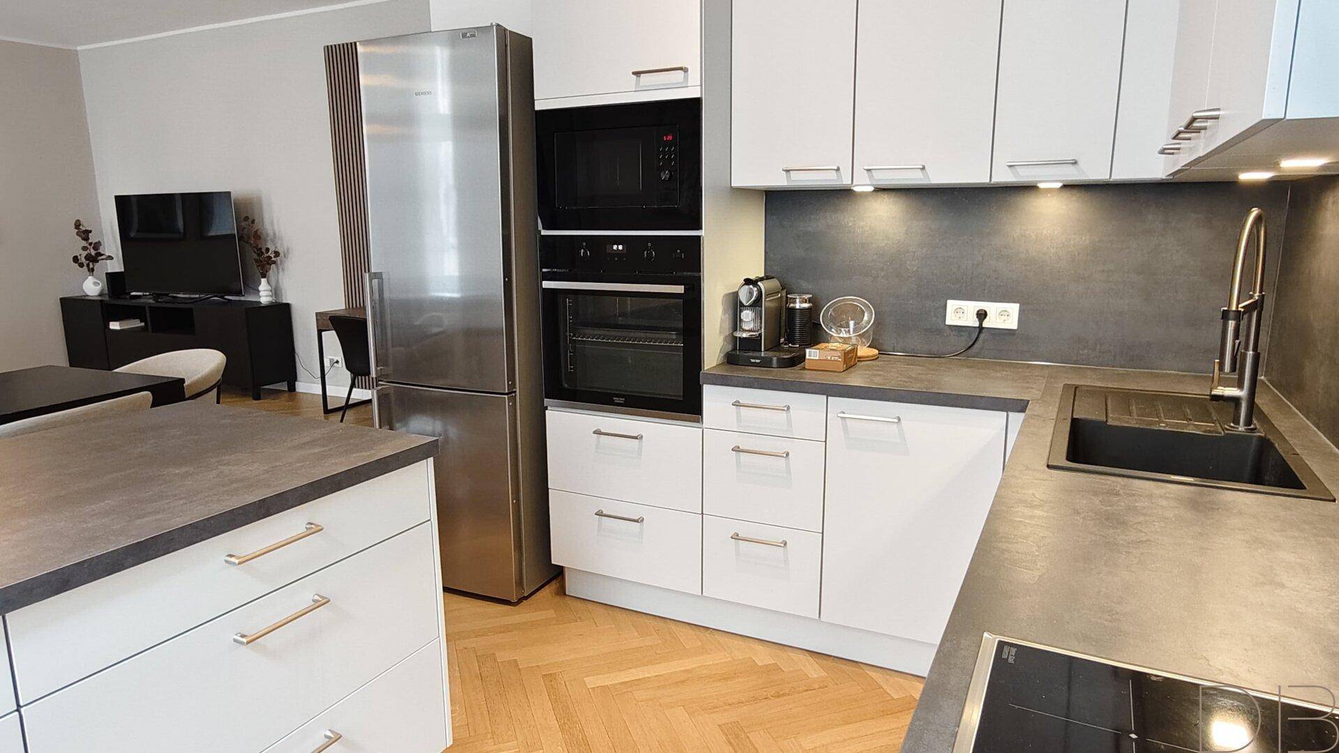 Helle, moderne Küche mit Edelstahlgeräten, Kochinsel und viel Stauraum.