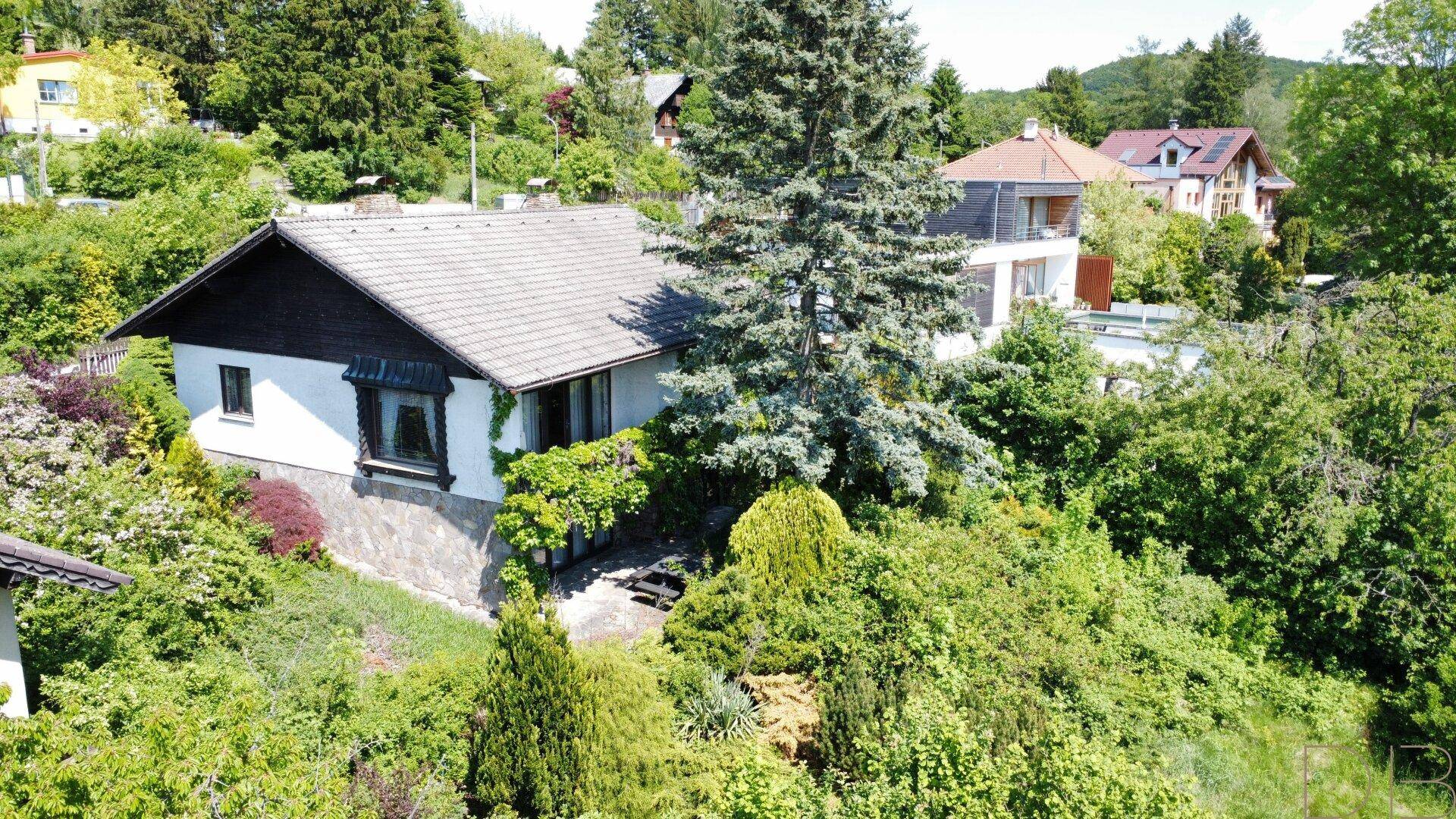 Einfamilienhaus in Hanglage, umgeben von üppiger Vegetation und mit Blick auf die Nachbarschaft.