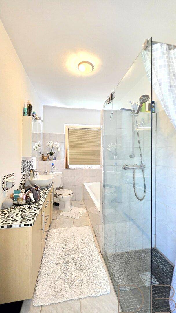 Modernes Badezimmer mit Duschkabine, Badewanne, Einzelwaschbecken und Fenster.