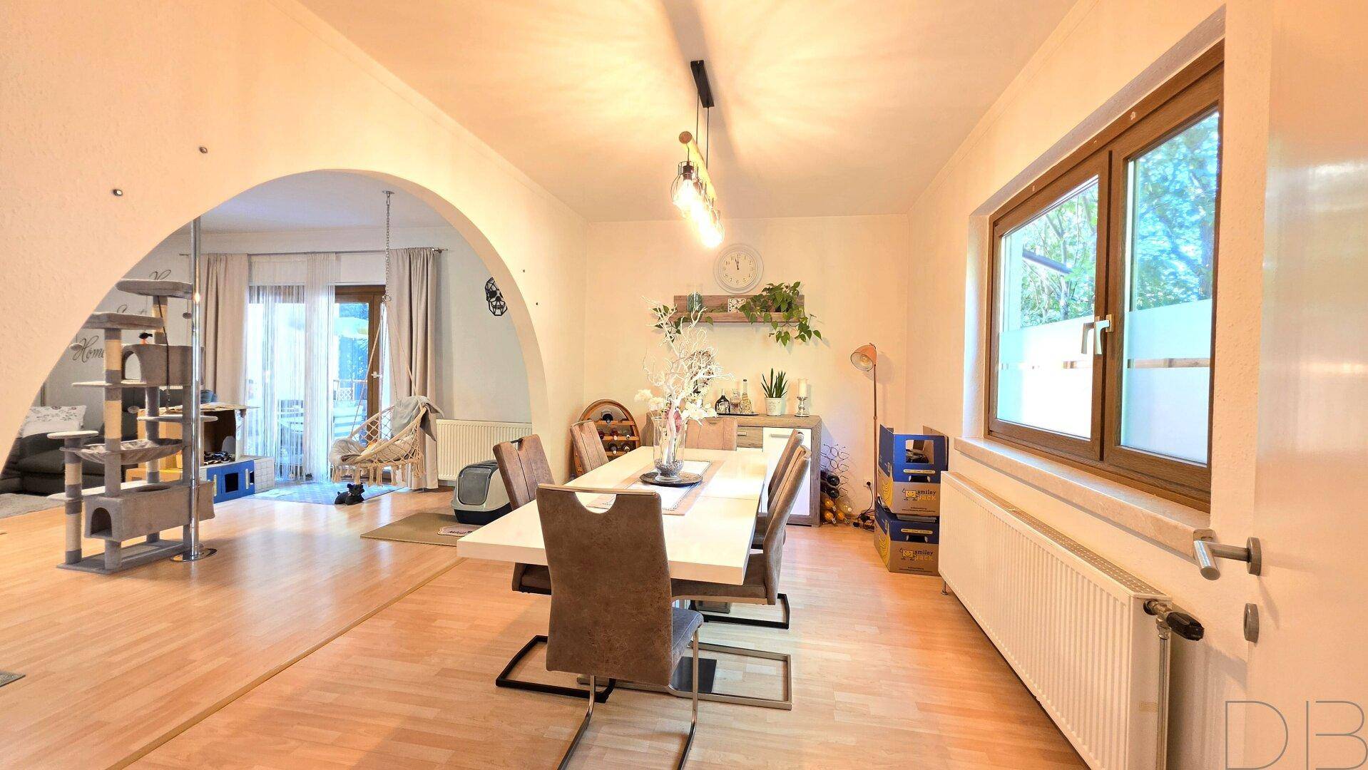 Heller Essbereich mit großem Tisch und Zugang zum Wohnzimmer durch einen eleganten Bogen.