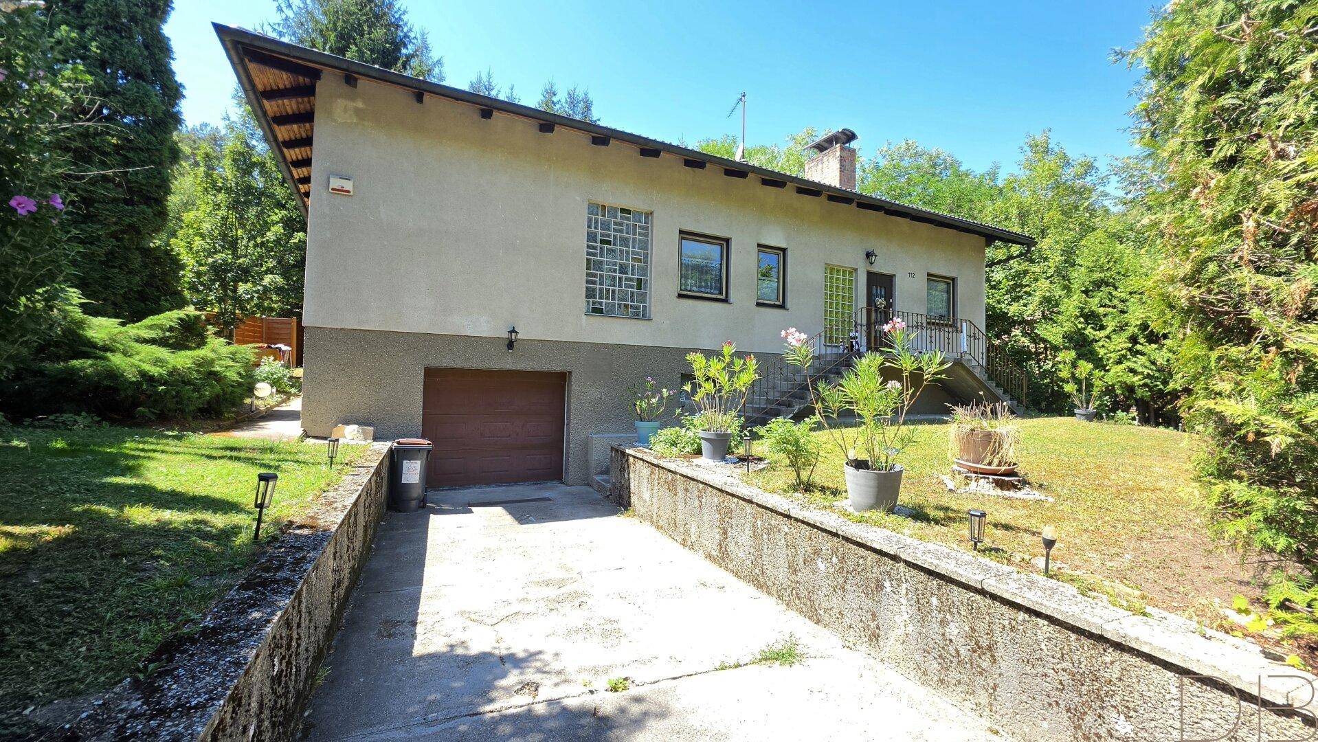 Vorderansicht des Hauses mit integrierter Garage und einer Zufahrt.