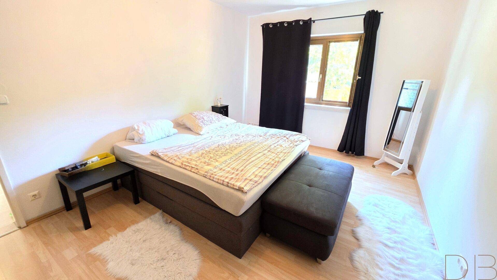 Gemütliches Schlafzimmer mit Doppelbett, Holzboden und großem Spiegel.