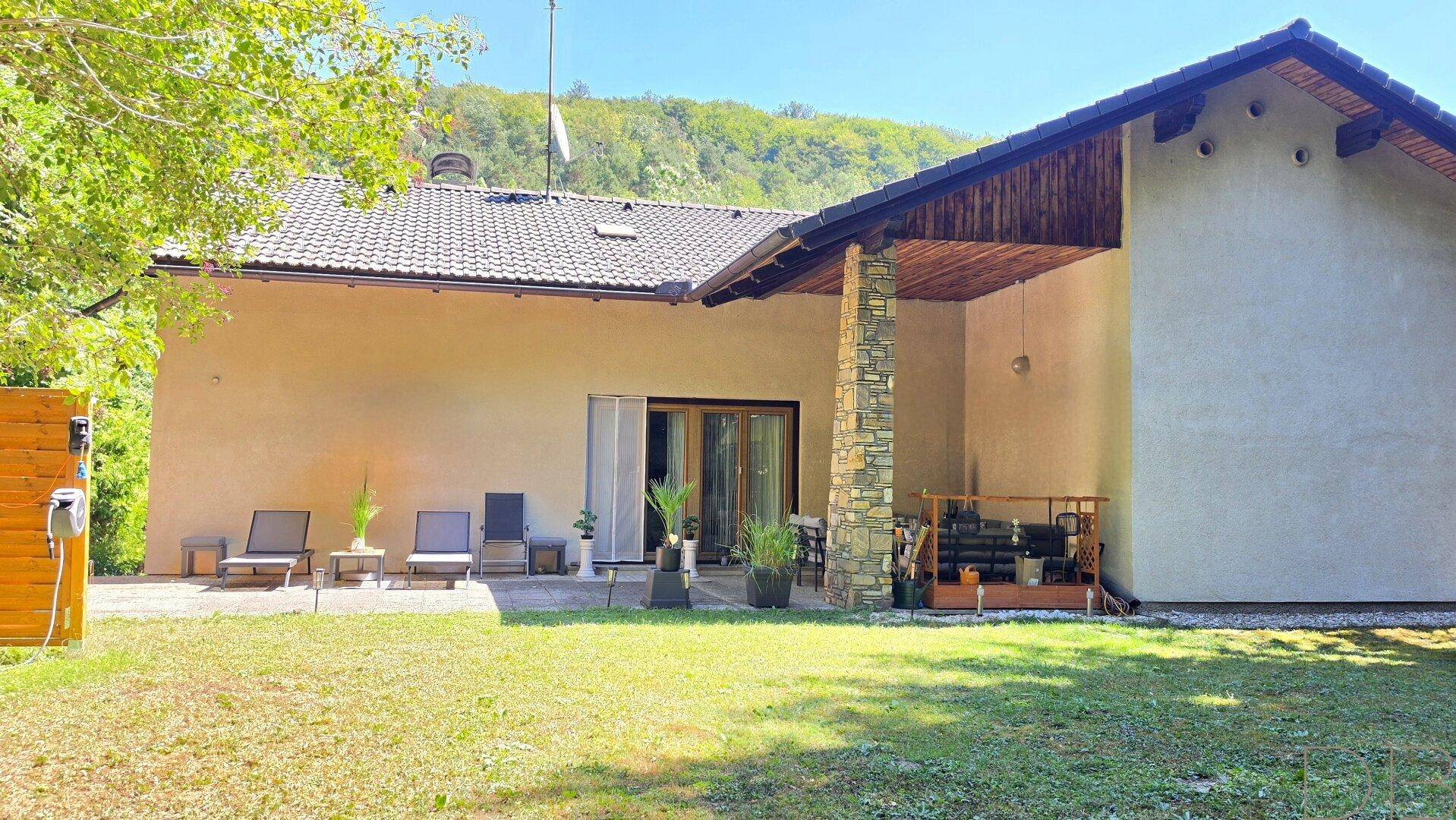 Weitläufiger Gartenbereich hinter dem Haus mit großer Rasenfläche und sonniger Terrasse.