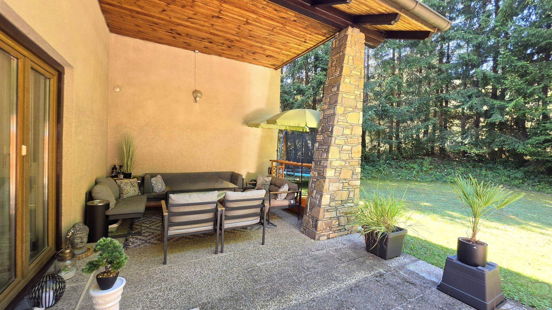 Überdachte Terrasse mit bequemen Gartenmöbeln und Blick ins Grüne, ideal zum Entspannen.