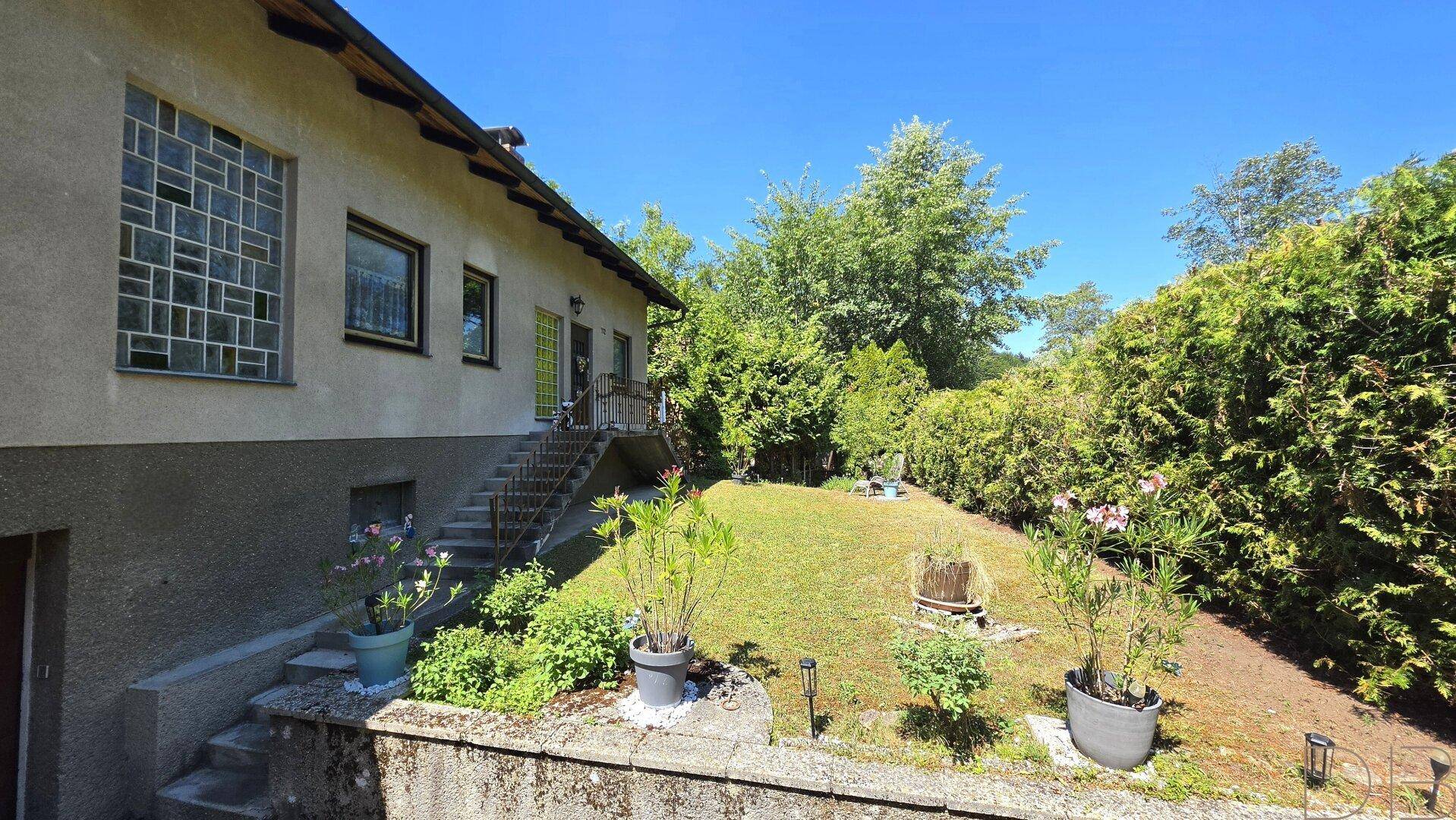 Seitenansicht des Hauses mit Treppe zum Eingang und einem terrassierten Gartenbereich.