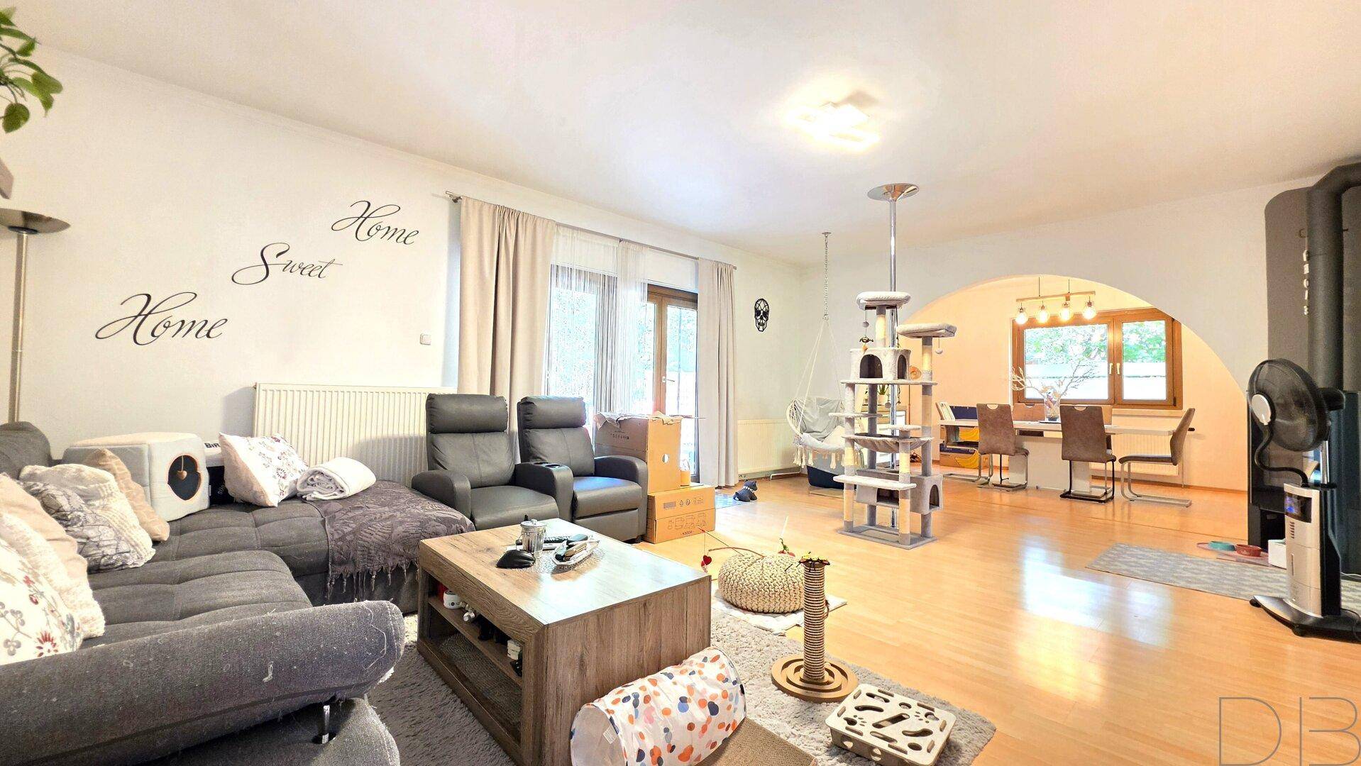 Helles Wohn- und Esszimmer mit Parkettboden, Kaminofen und Zugang zur Terrasse.