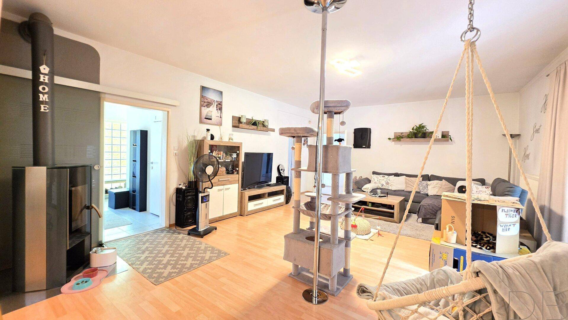 Geräumiges Wohnzimmer mit Holzboden, Kaminofen und viel natürlichem Licht.